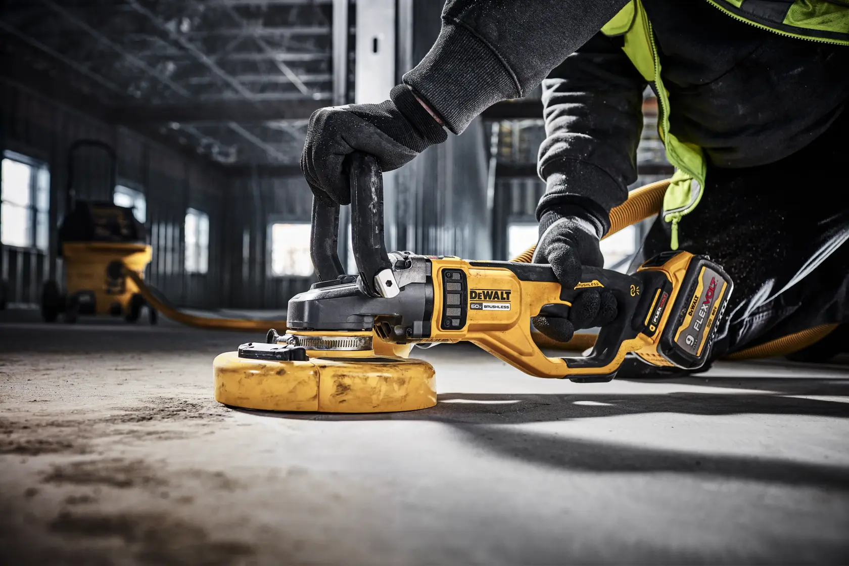 Person wearing protective clothing and gloves using a DEWALT cordless angle grinder to cut a metal bar, generating bright sparks.