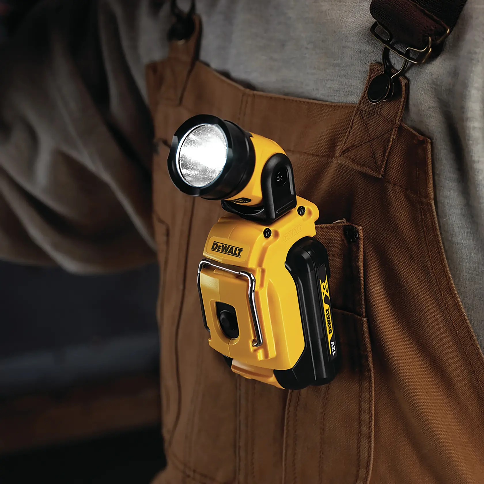 DEWALT portable LED flashlight illuminates an electrical panel while a person uses a DEWALT cordless drill to fasten wires inside the panel.