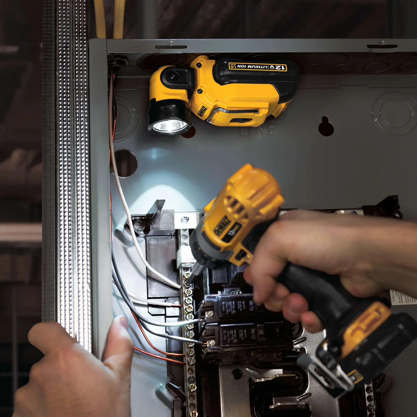 A DEWALT DCL510 portable LED work light clipped onto the front pocket of brown overalls. The light is turned on and provides hands-free illumination.