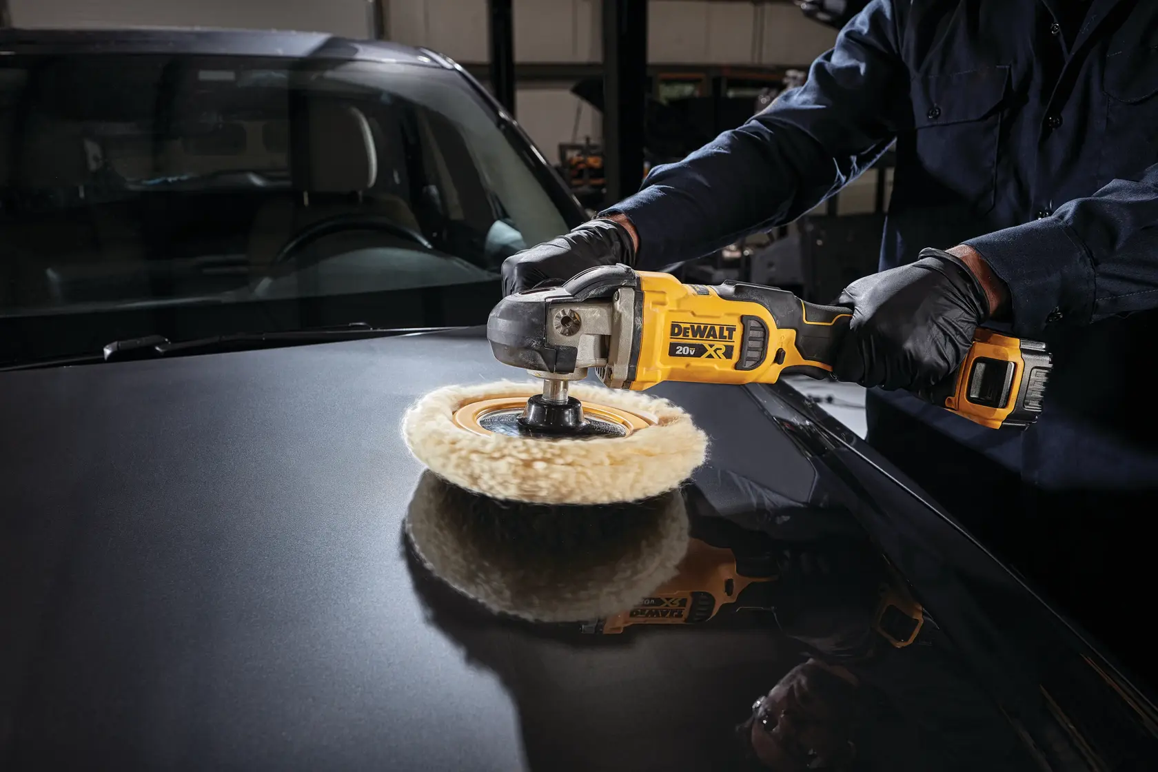 A person wearing black gloves is using a DEWALT 20V XR cordless polisher to polish the hood of a car.