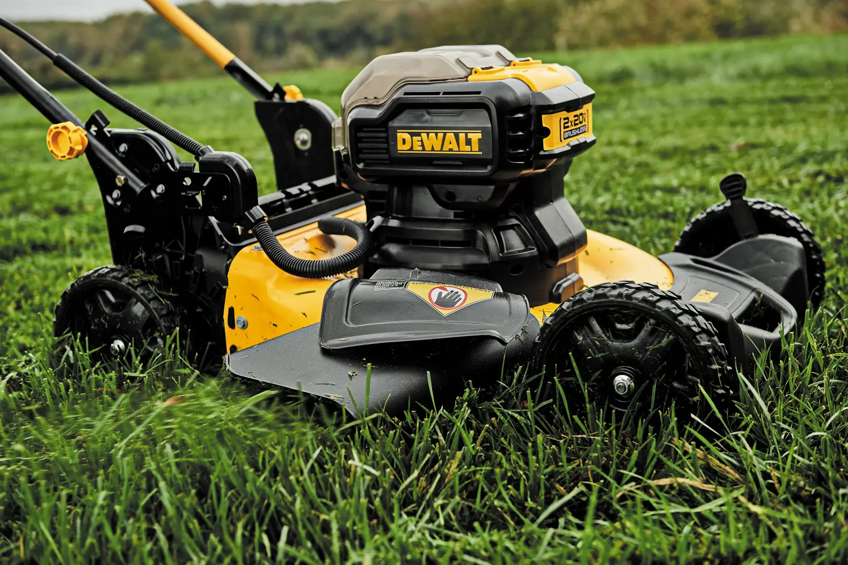 A DEWALT branded cordless lawn mower with large wheels is shown cutting grass outdoors.