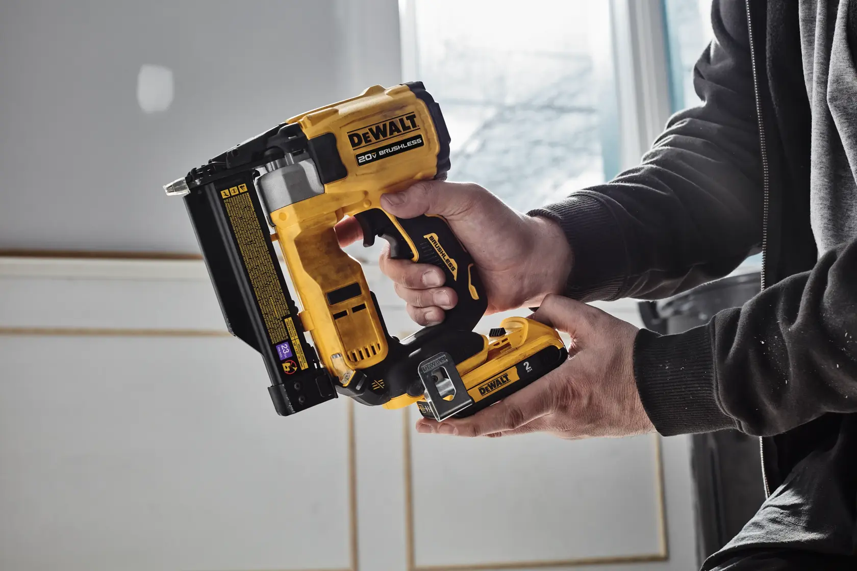 Image shows a DEWALT 20V MAX* Brushless cordless tool kit, model DCN623D1. The kit includes a yellow and black DEWALT 20V brushless nailer, a compact lithium-ion 2.0Ah battery pack, a 20V MAX* charger, and a black and yellow DEWALT branded kit bag. The background text lists the included items.