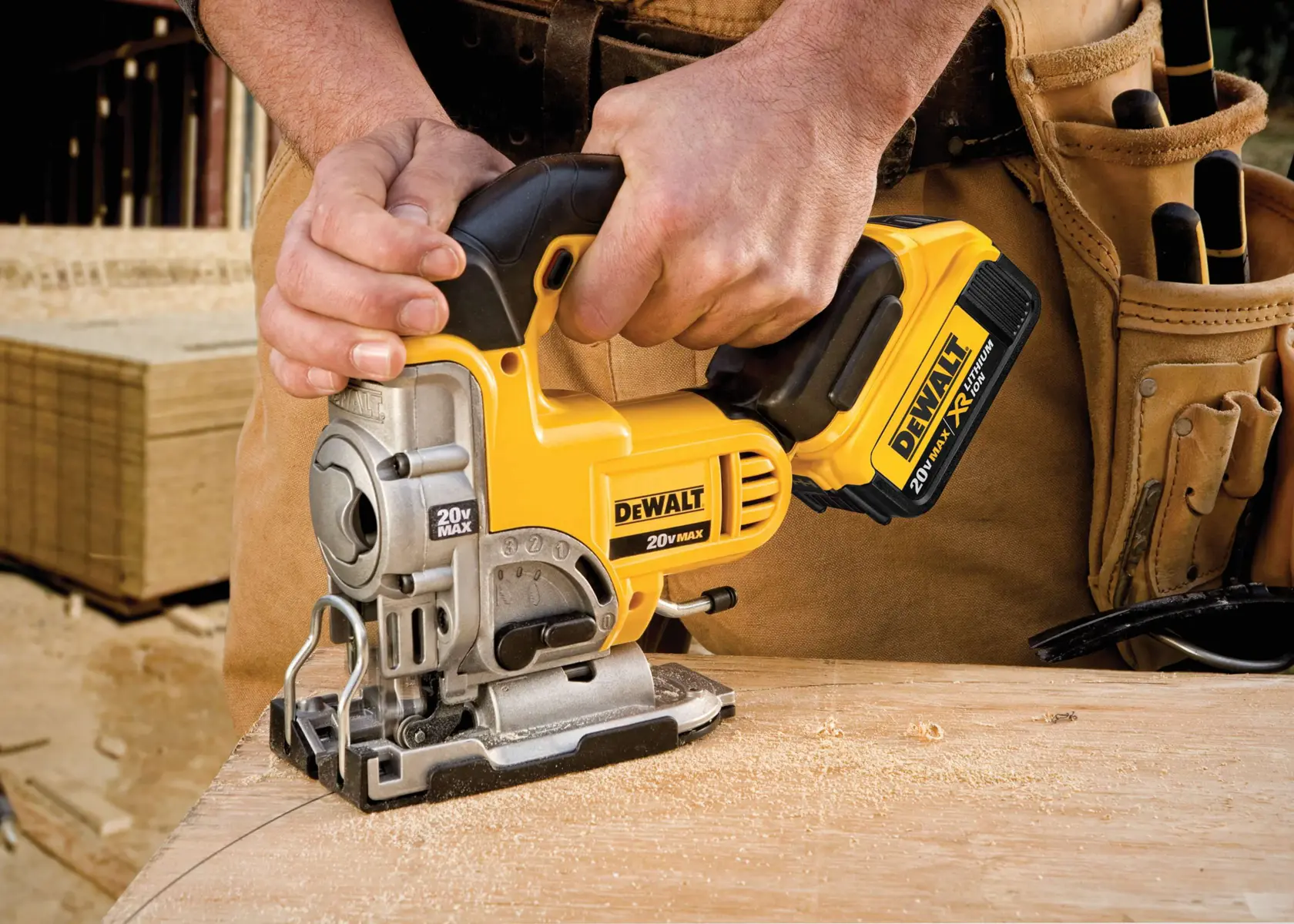 A close-up view of a person using a yellow DEWALT 20V MAX cordless jigsaw to cut wood, with a carpenter’s tool belt visible in the background.