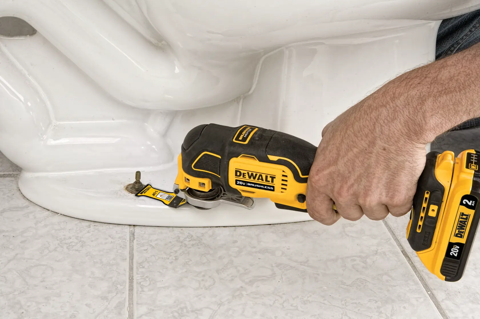 A person is using a yellow and black DEWALT 20V cordless oscillating multi-tool to cut or shape a piece of white plastic pipe attached to a concrete block wall.