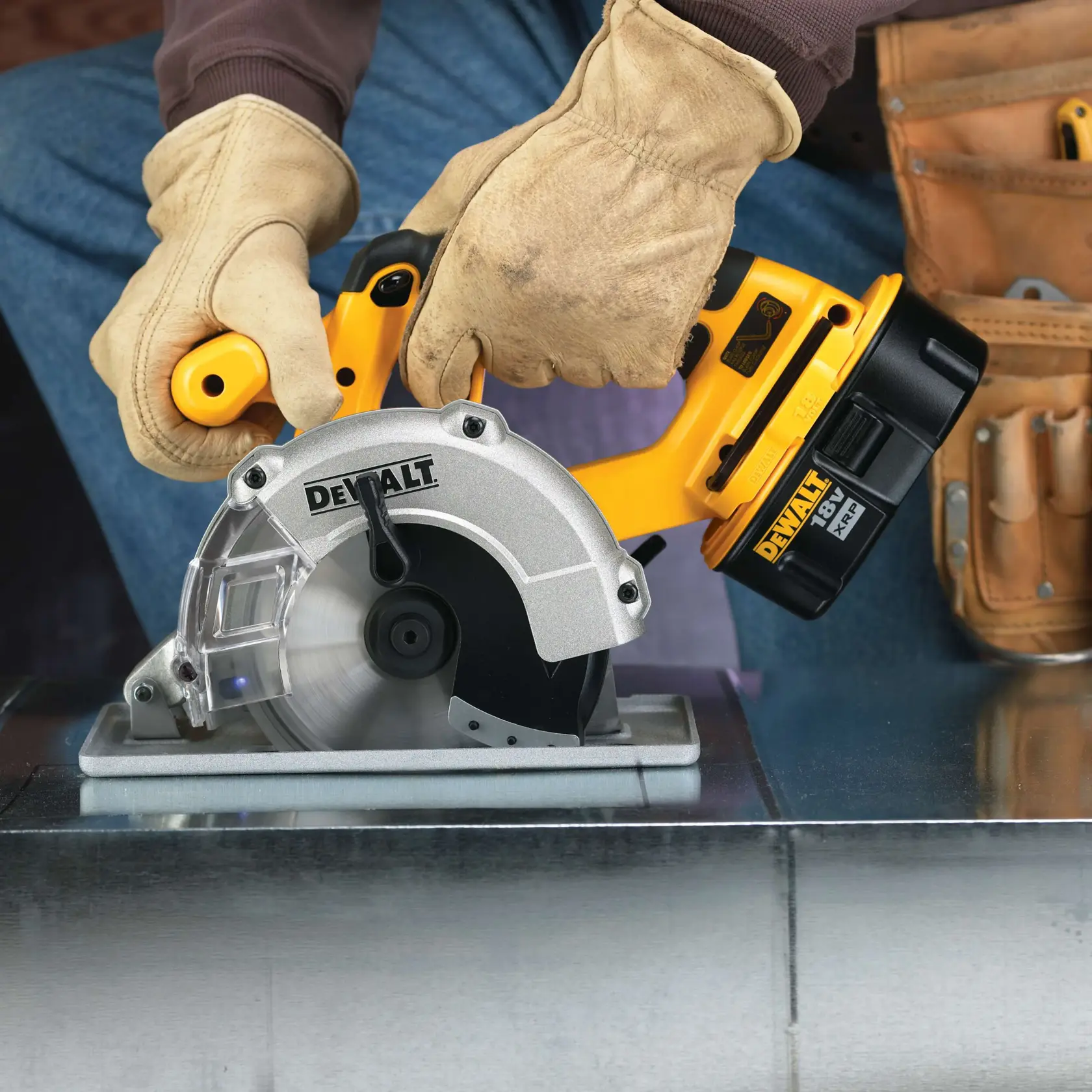 A person wearing beige work gloves uses a DEWALT cordless circular saw to cut metal, with a tool belt visible in the background.