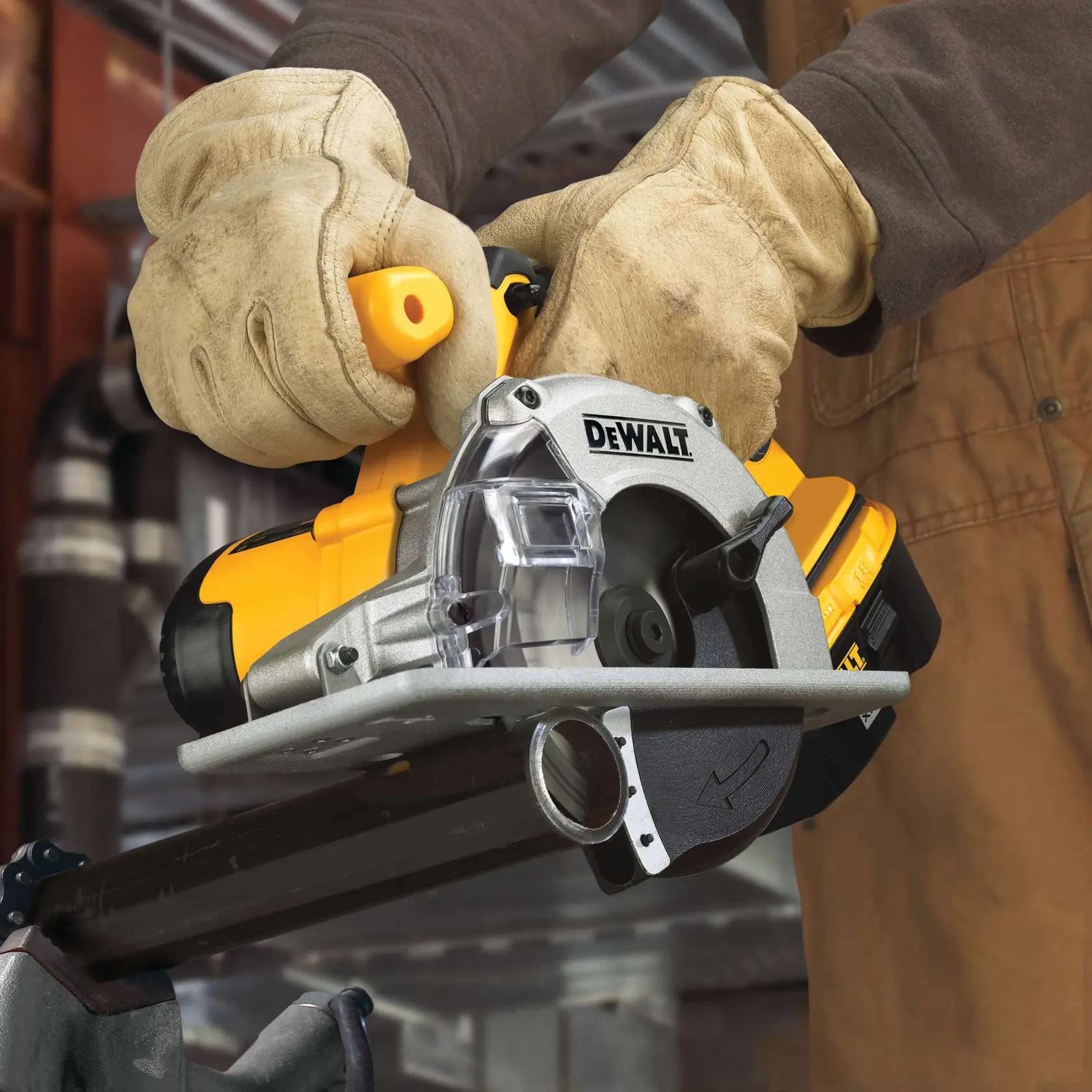 A close-up of a person wearing work gloves using a DEWALT cordless circular saw to cut through a metal pipe in an industrial setting.