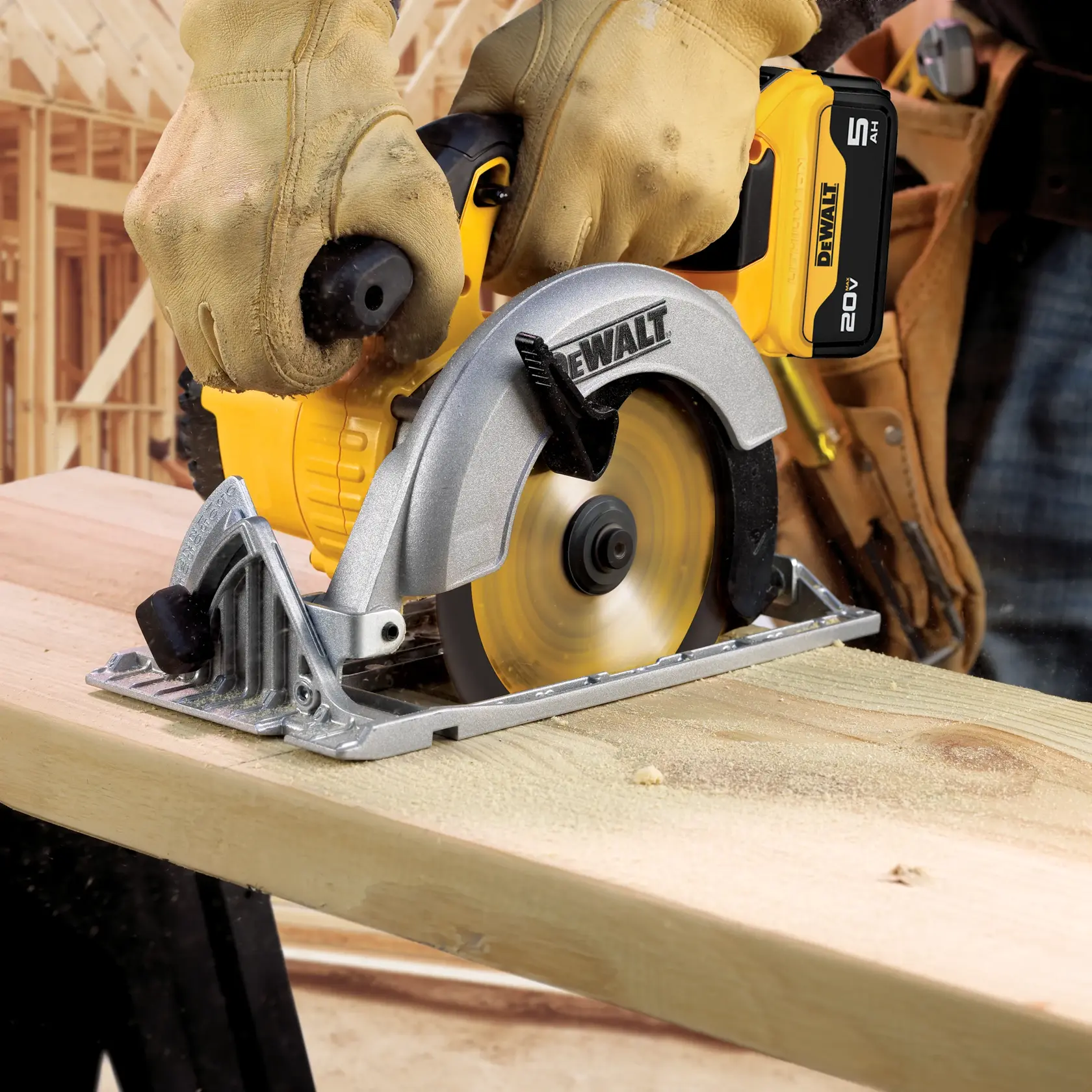 A person wearing work gloves uses a DEWALT cordless circular saw to cut a piece of wood. The saw is powered by a 20V lithium-ion battery. The scene takes place on a construction site with wooden framing in the background.