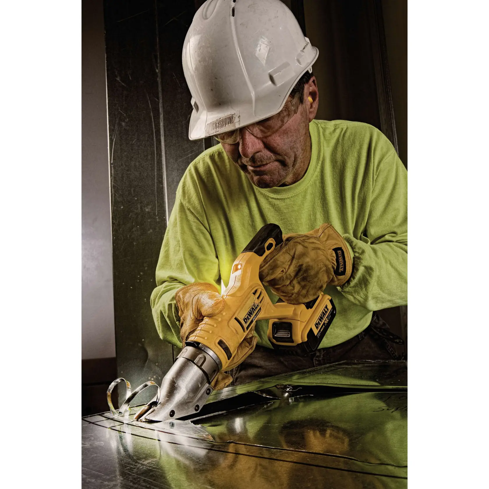 A person wearing a white hard hat and safety gloves is using a yellow DEWALT cordless metal shear (model DCS494M2) to cut through a sheet of metal.