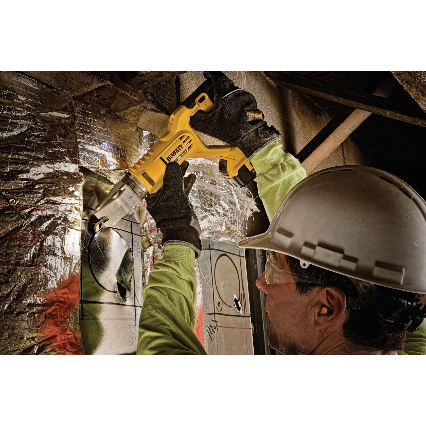 A person wearing protective gloves and a hard hat uses a yellow DEWALT power tool to cut a circular shape into a metallic surface covered with insulation. The environment appears to be an industrial or construction site.