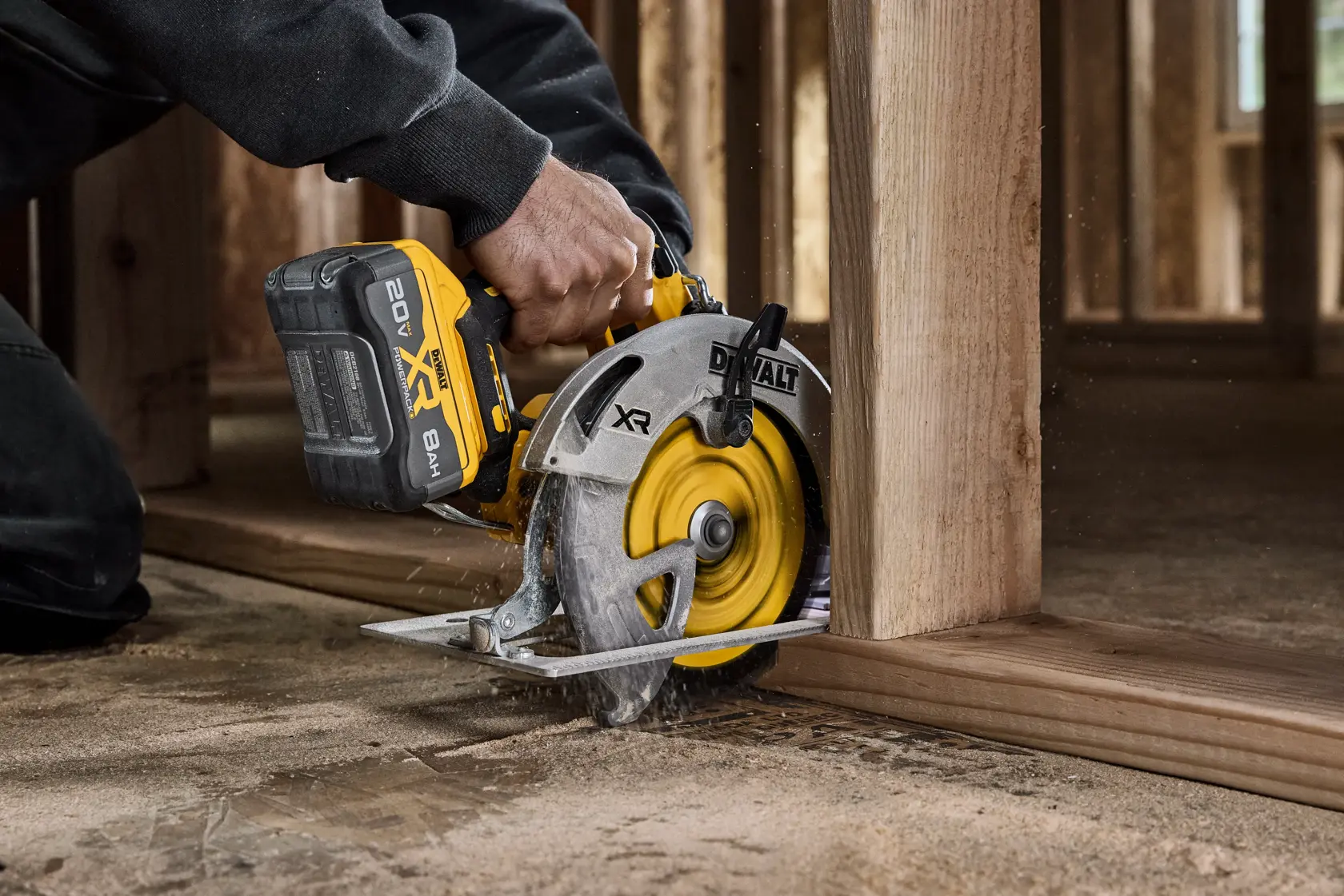 A person using a DEWALT cordless circular saw to cut a wooden beam at a construction site. The saw displays the XR and 20V Max branding.