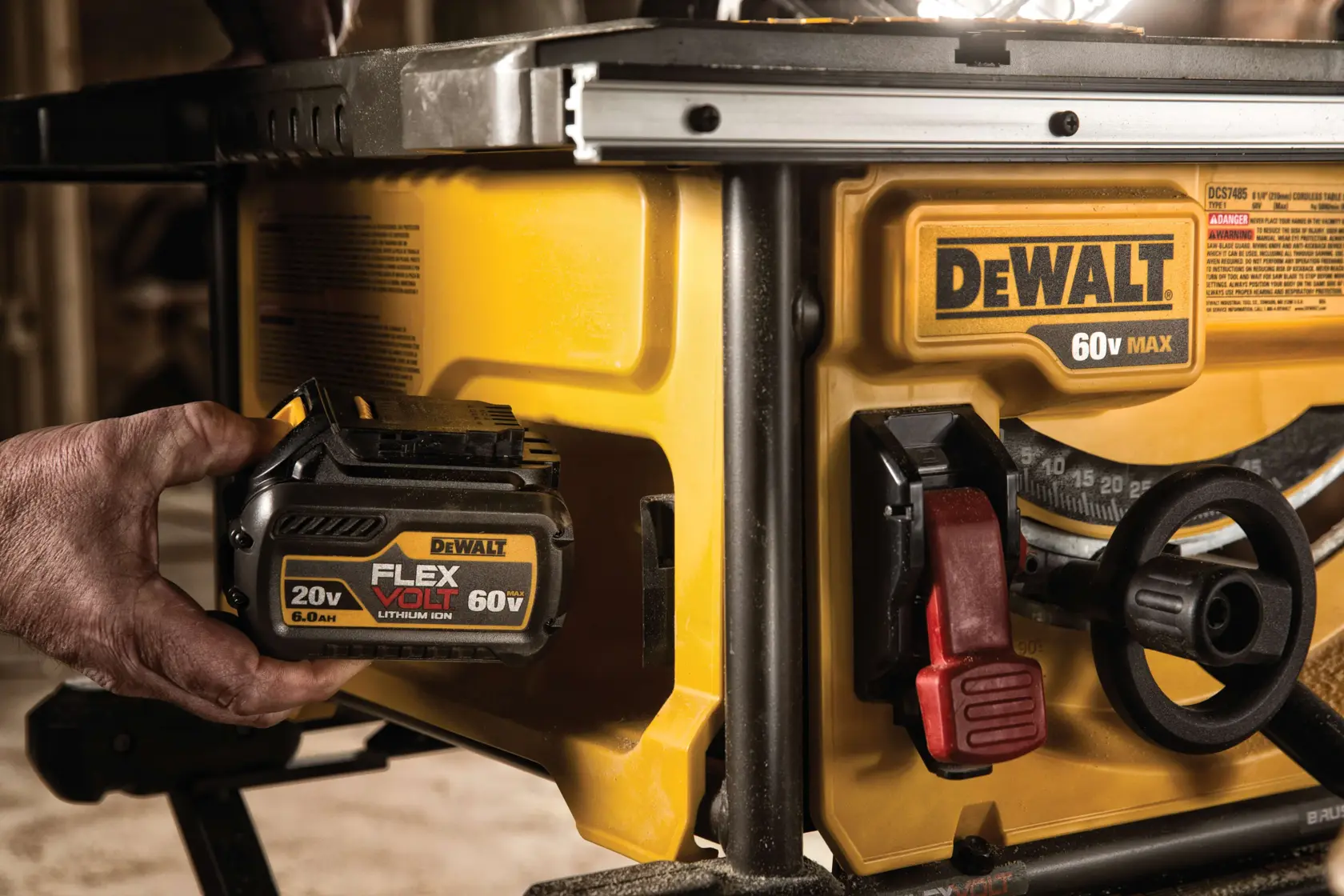 Close-up of a DEWALT 60V Max table saw with a person inserting a FLEXVOLT lithium-ion battery. The saw features yellow and black coloring, visible DEWALT branding, and control knobs.
