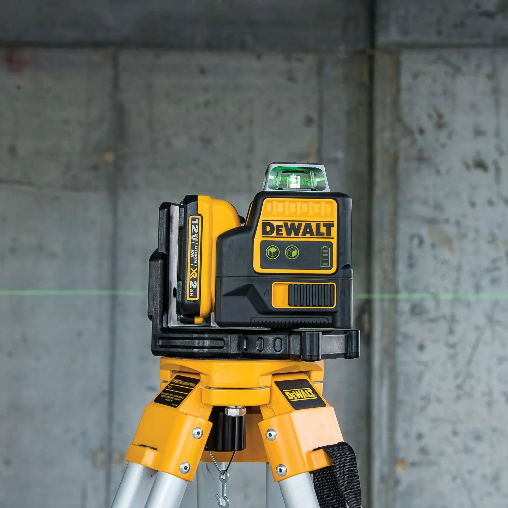 A DEWALT DW0811LG green laser level is mounted on a tripod, projecting a horizontal green laser line onto a concrete wall in the background.