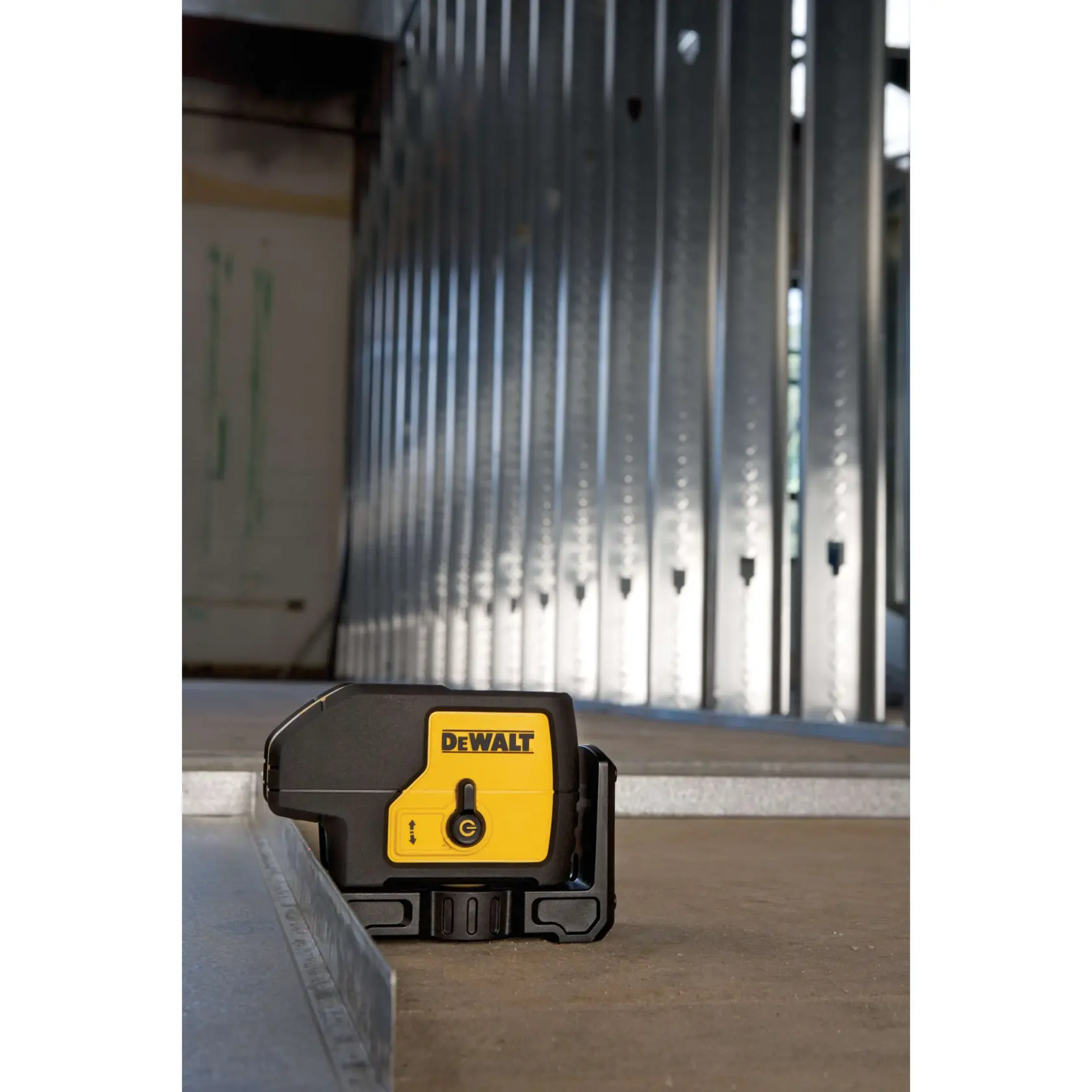 DEWALT DW083K laser level tool in use at a construction site with metal wall framing.