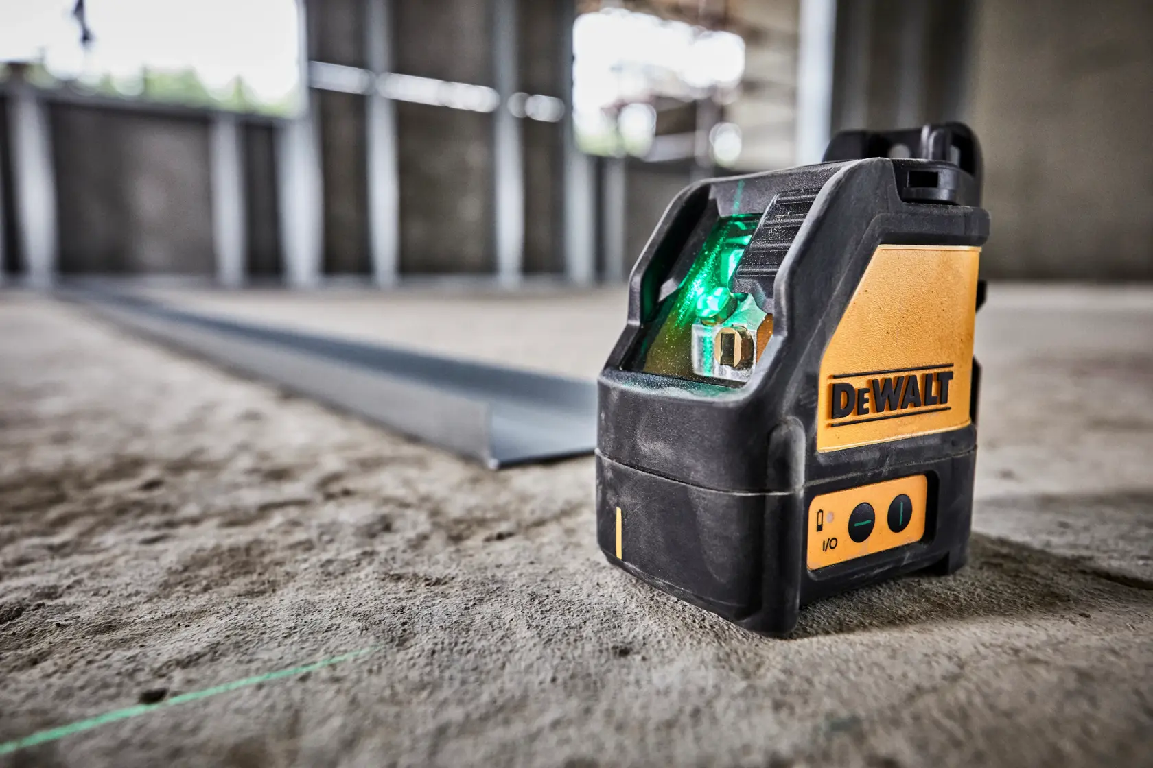 DEWALT green beam laser level DW088CG placed on a concrete floor inside a construction site.