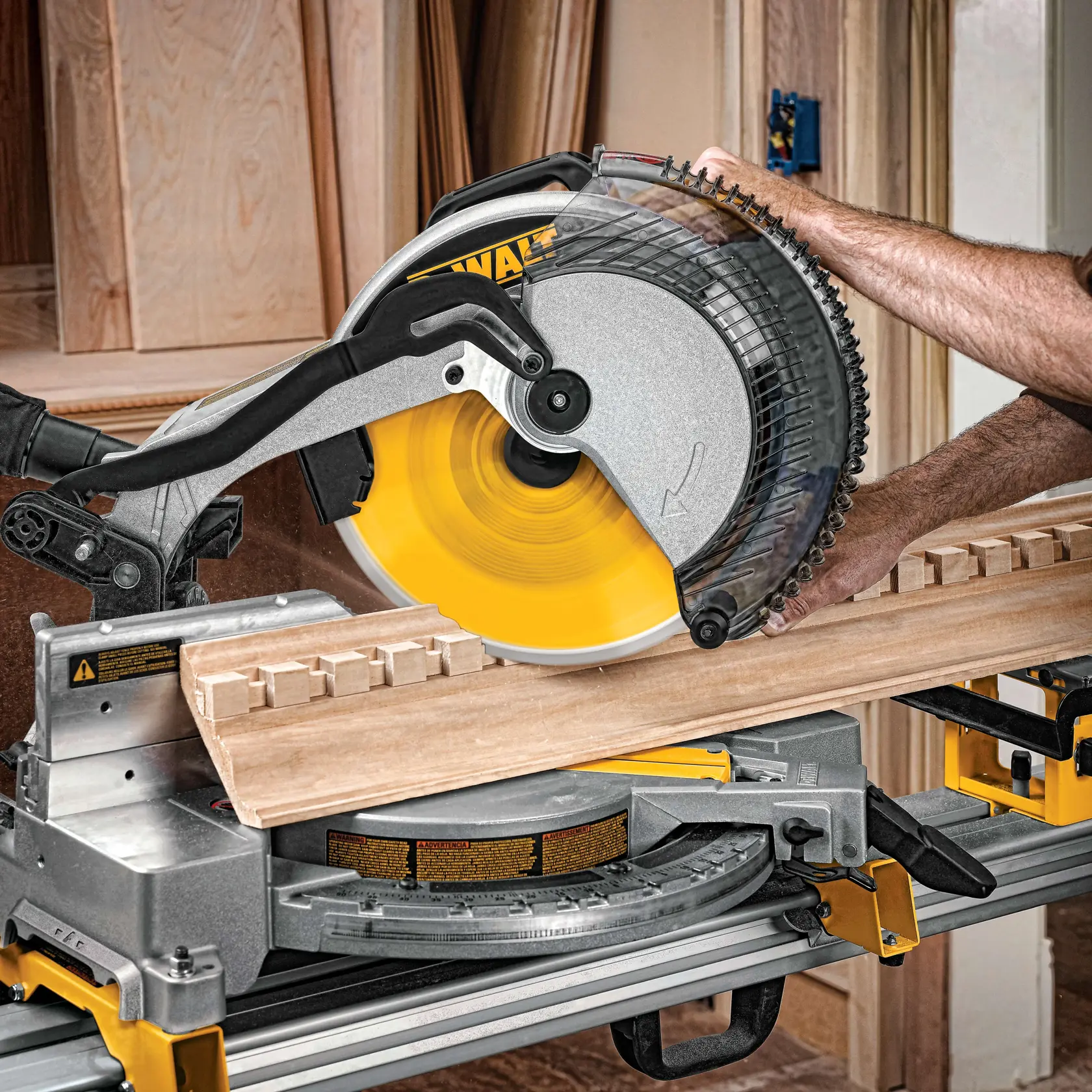 Une personne utilise une scie à onglet DEWALT pour couper une moulure décorative en bois dans un atelier.