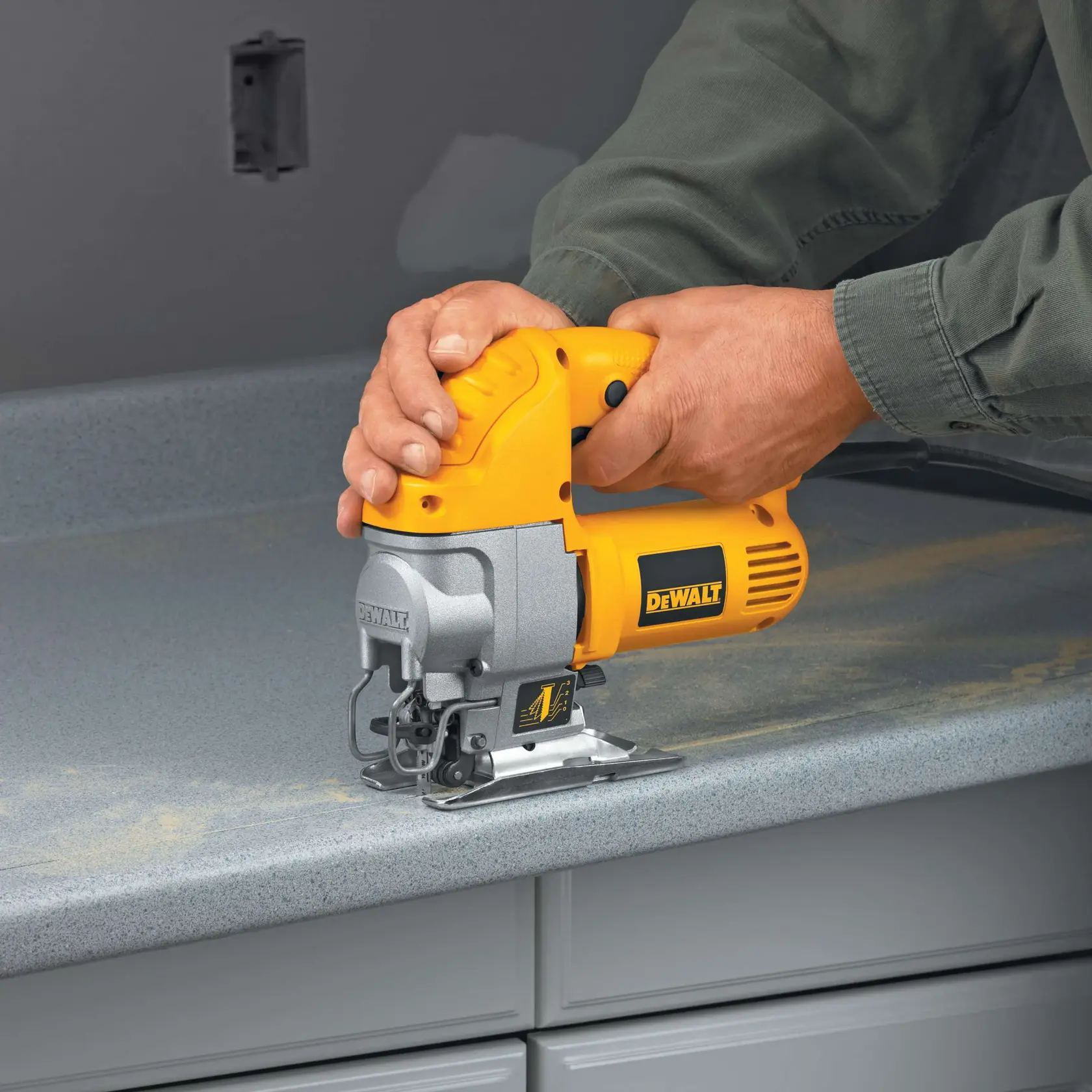 A person using a yellow DEWALT jigsaw to cut a piece of wood on a workbench.