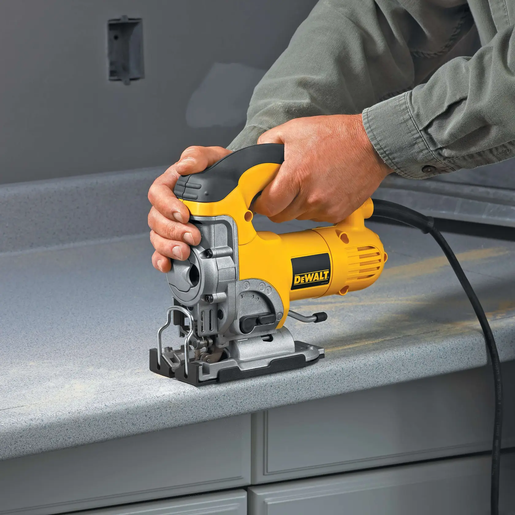 Person using a DEWALT jigsaw tool to cut a countertop surface indoors.