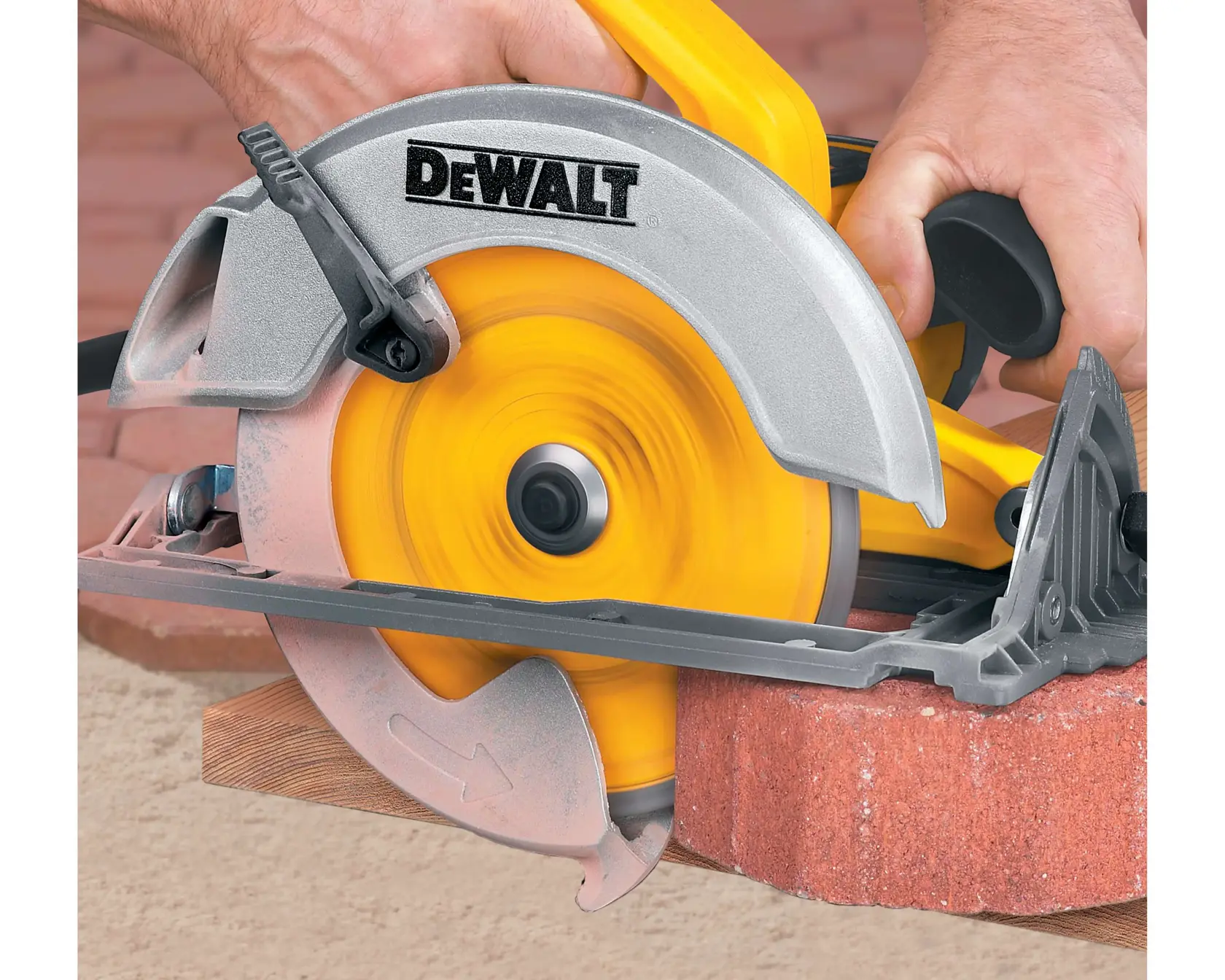 A close-up view of a DEWALT circular saw being used to cut through a brick. The person operating the saw is gripping the handle, and the yellow blade is spinning rapidly.