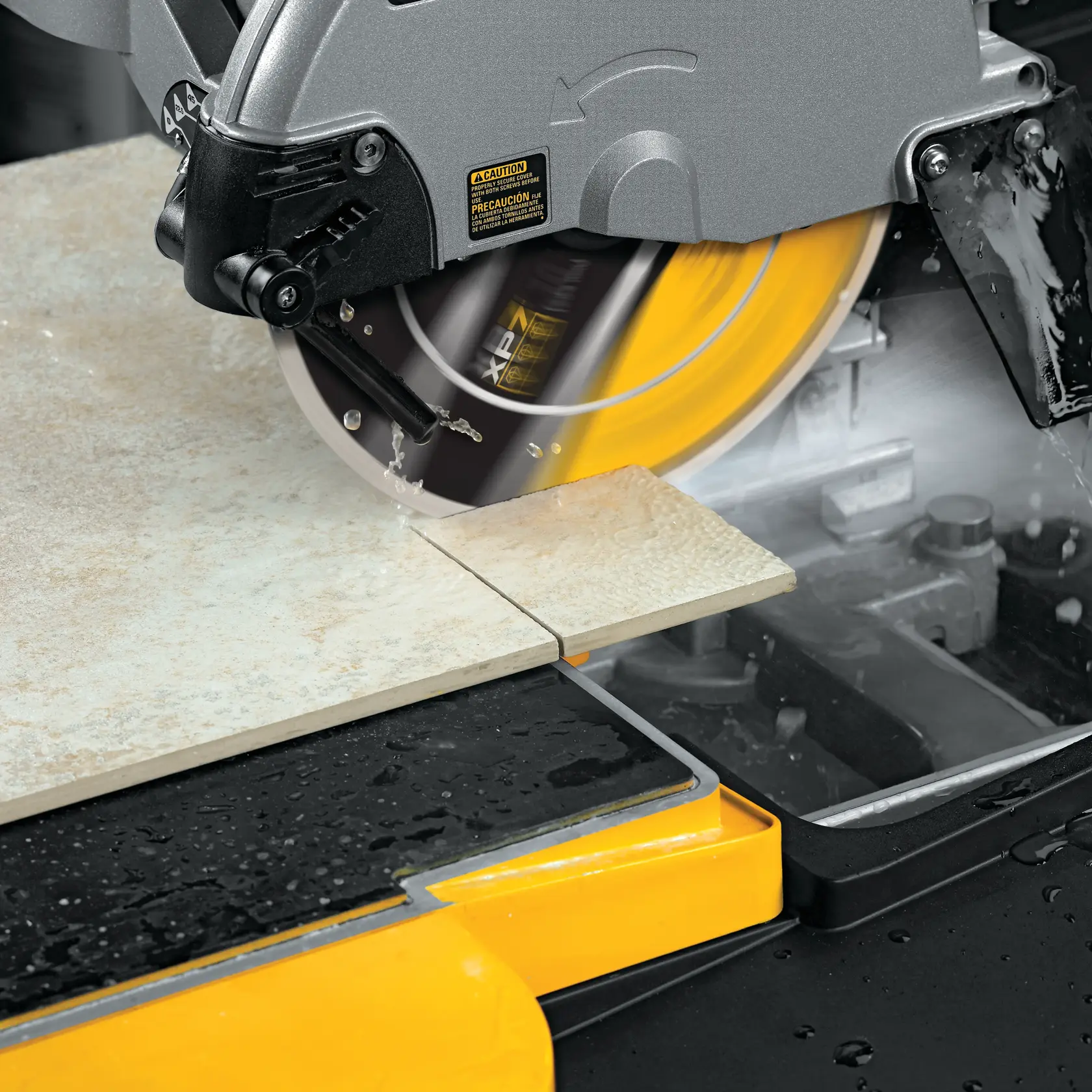 A DEWALT tile saw in use, cutting a ceramic tile. Water is being sprayed onto the cutting area to cool the blade and reduce dust. The saw features a yellow XP7 diamond blade and is set on a workbench with a wet tray.