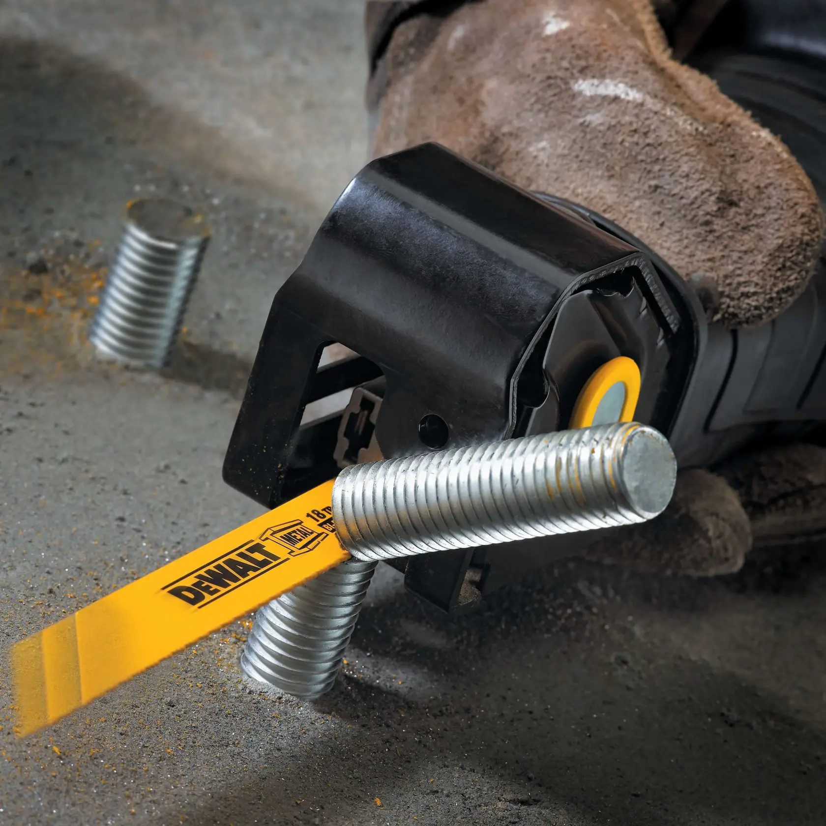 Close-up of a DEWALT reciprocating saw cutting through a metal threaded rod on a concrete surface, with a gloved hand holding the tool.