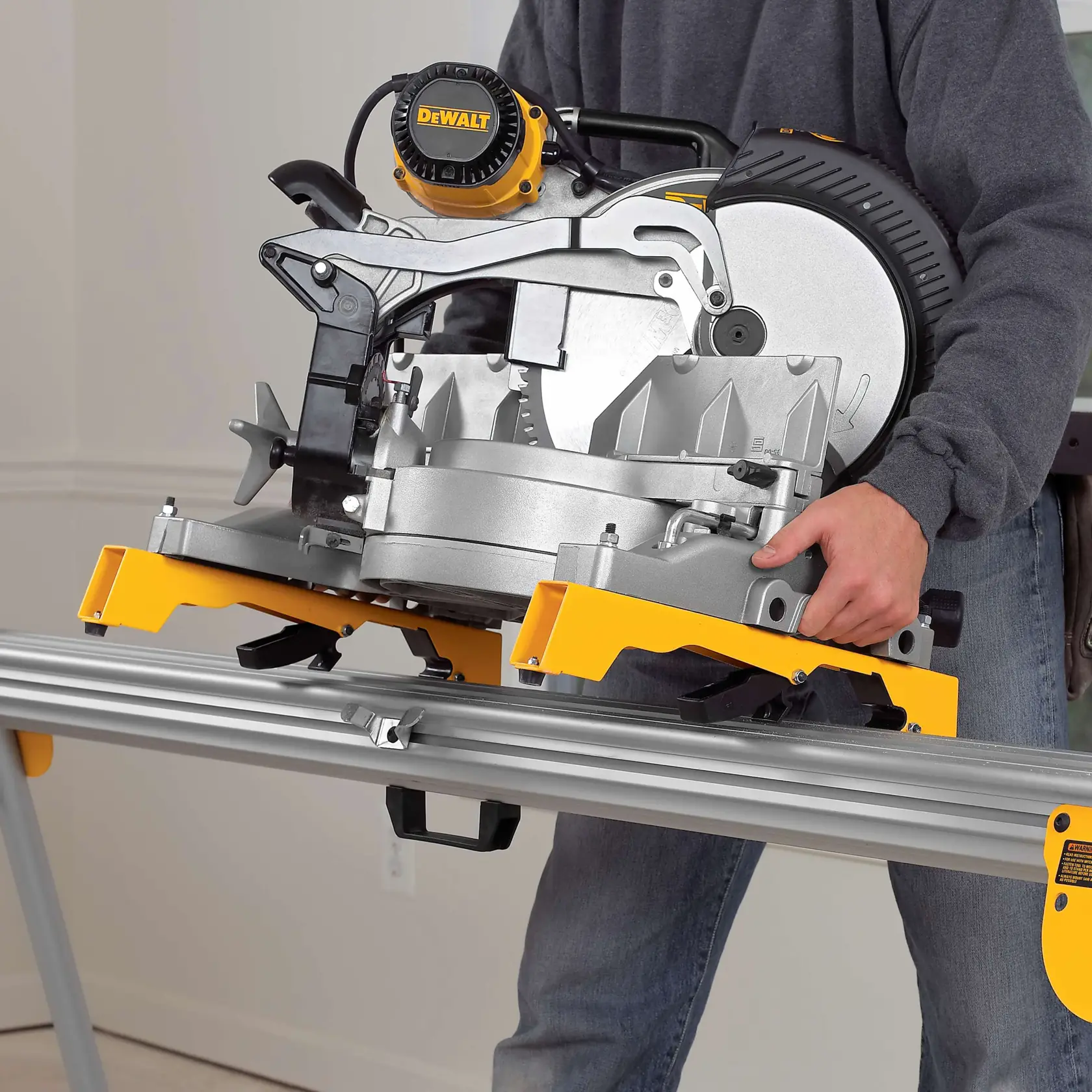 A person is mounting a DEWALT miter saw onto a metal saw stand using yellow brackets. The image highlights the secure attachment mechanism for woodworking and construction purposes.