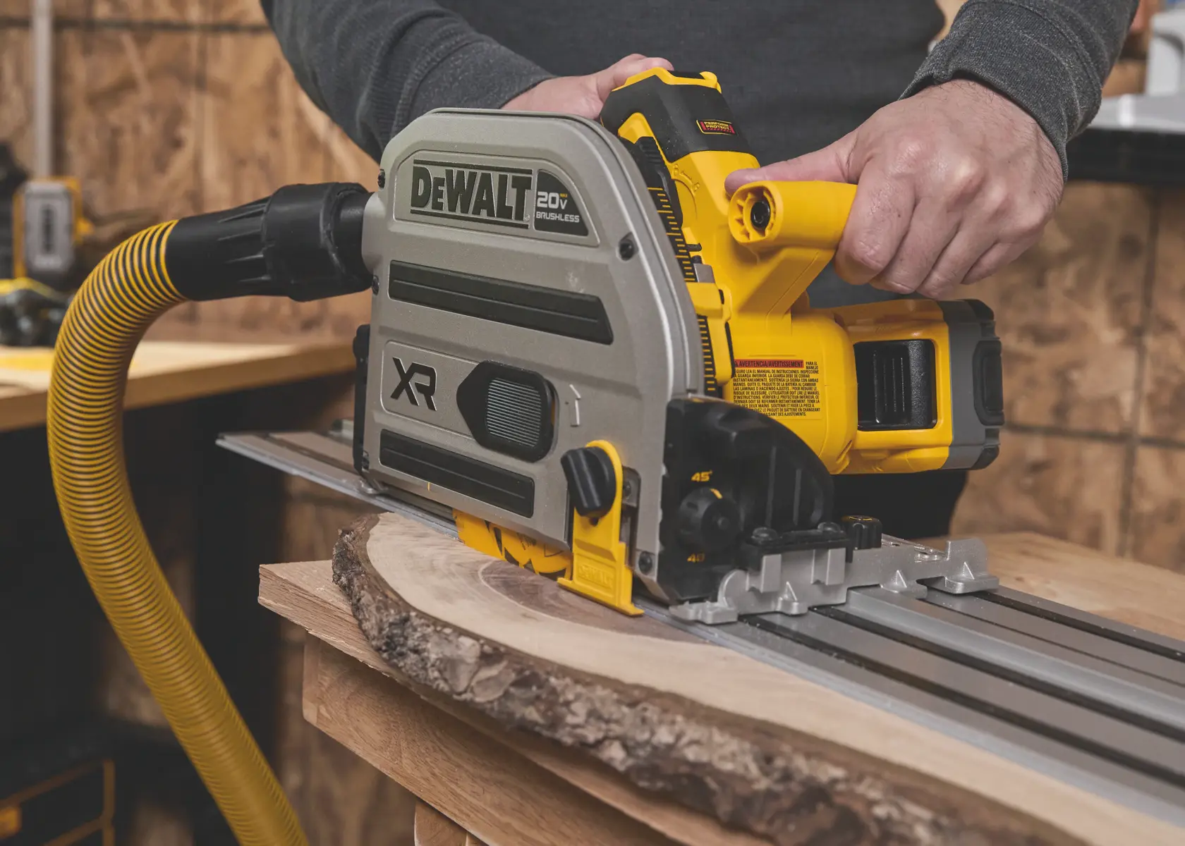 Scie plongeante sans fil DEWALT coupant du bois sur rail métallique dans un atelier.