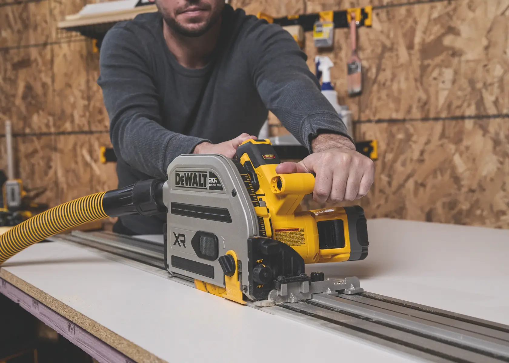 Personne utilisant une scie sur rail DEWALT XR pour couper du bois sur un établi dans un atelier.
