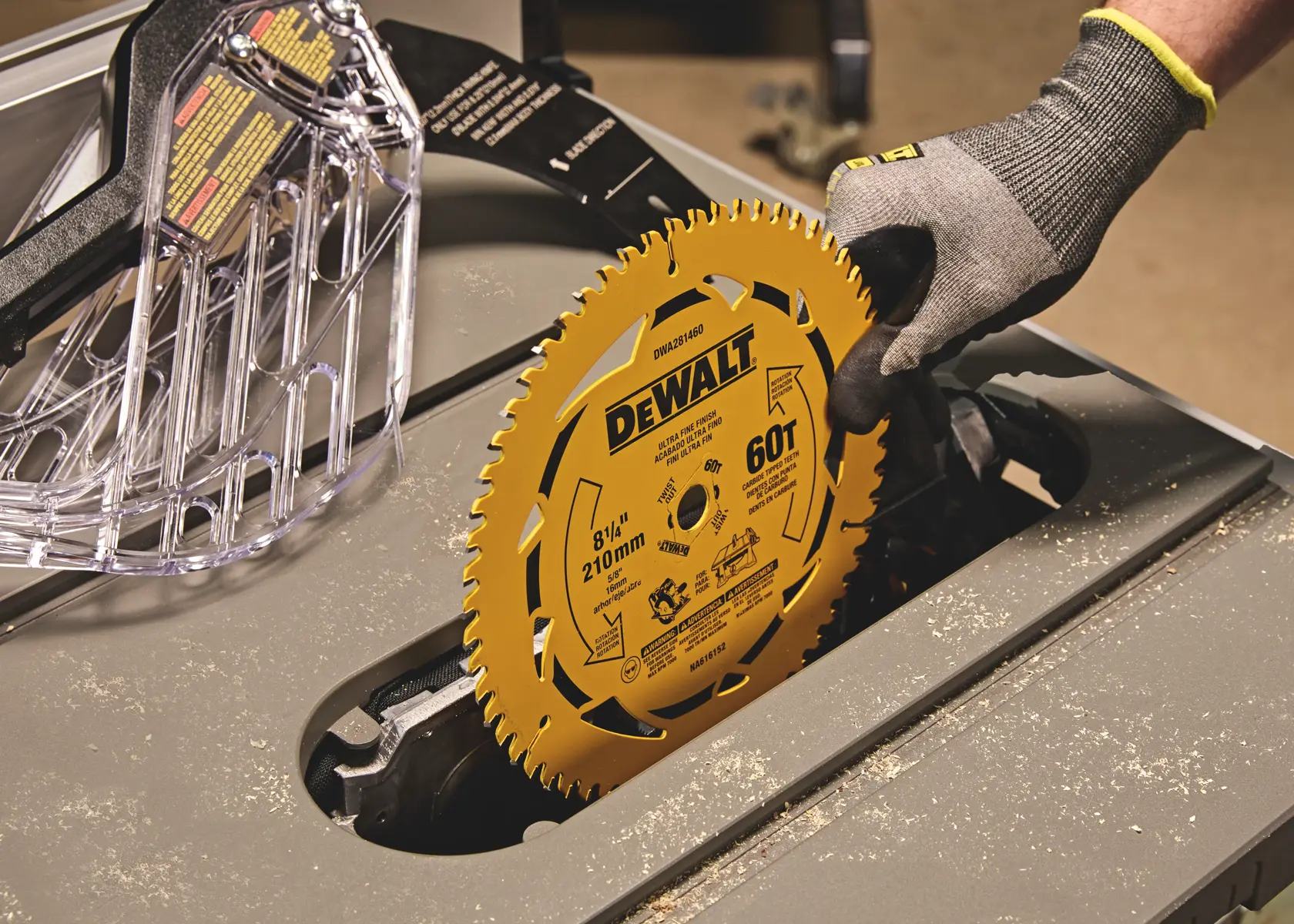 DEWALT saw blade being installed in a table saw by a gloved hand. Protective guard visible nearby.