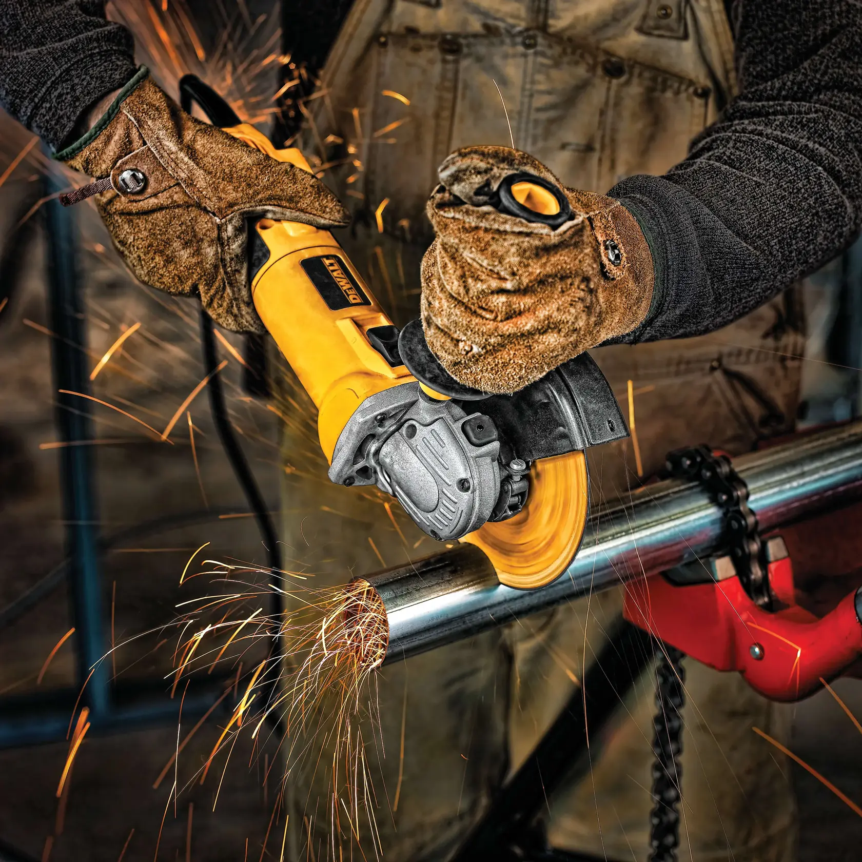A person wearing protective gloves uses a yellow DEWALT angle grinder to cut a metal pipe, producing sparks.