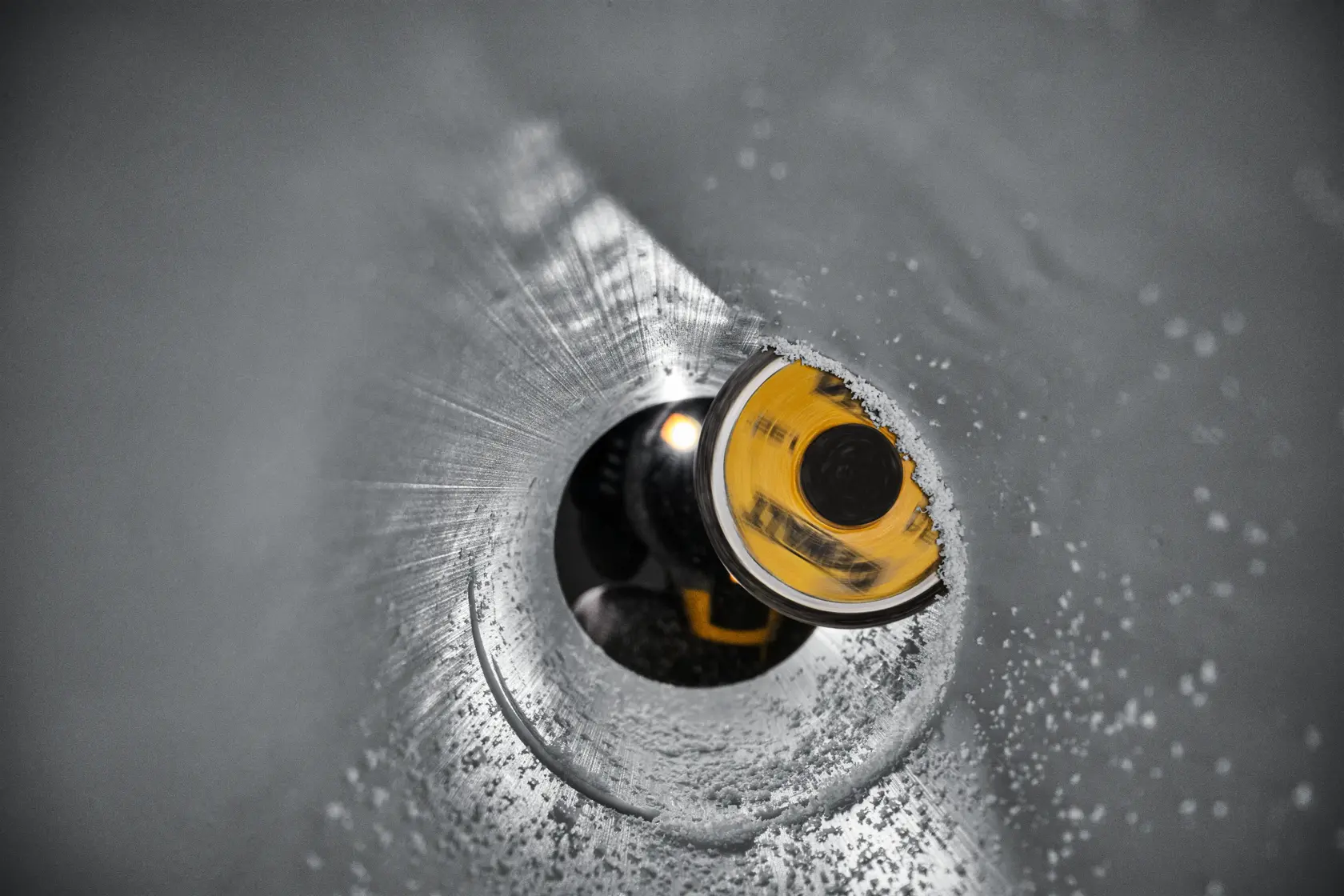 DEWALT tool with a circular yellow blade cutting into a metal pipe, creating a smooth, round hole.