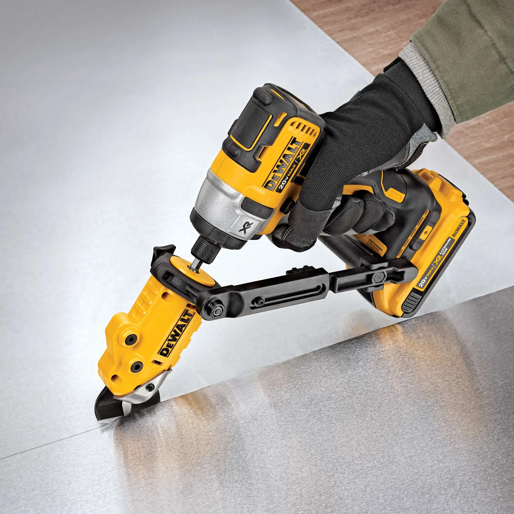 A DEWALT DWASHRIR power tool attachment being used to cut a sheet of metal, held by a gloved hand.