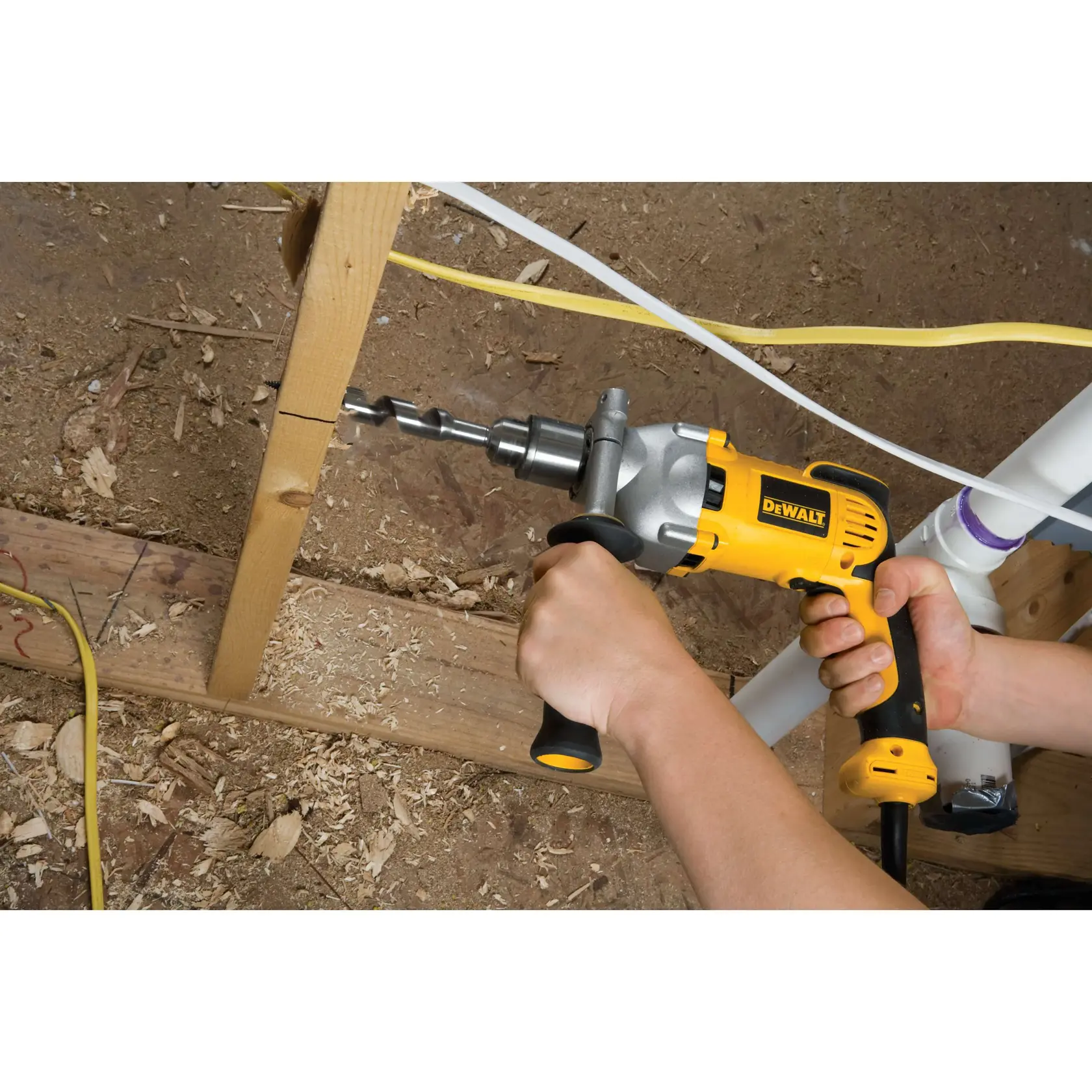 A yellow DEWALT power drill with a soft grip handle and two-finger trigger is shown in use drilling through wood, with wood shavings flying. The product emphasizes comfort and control.
