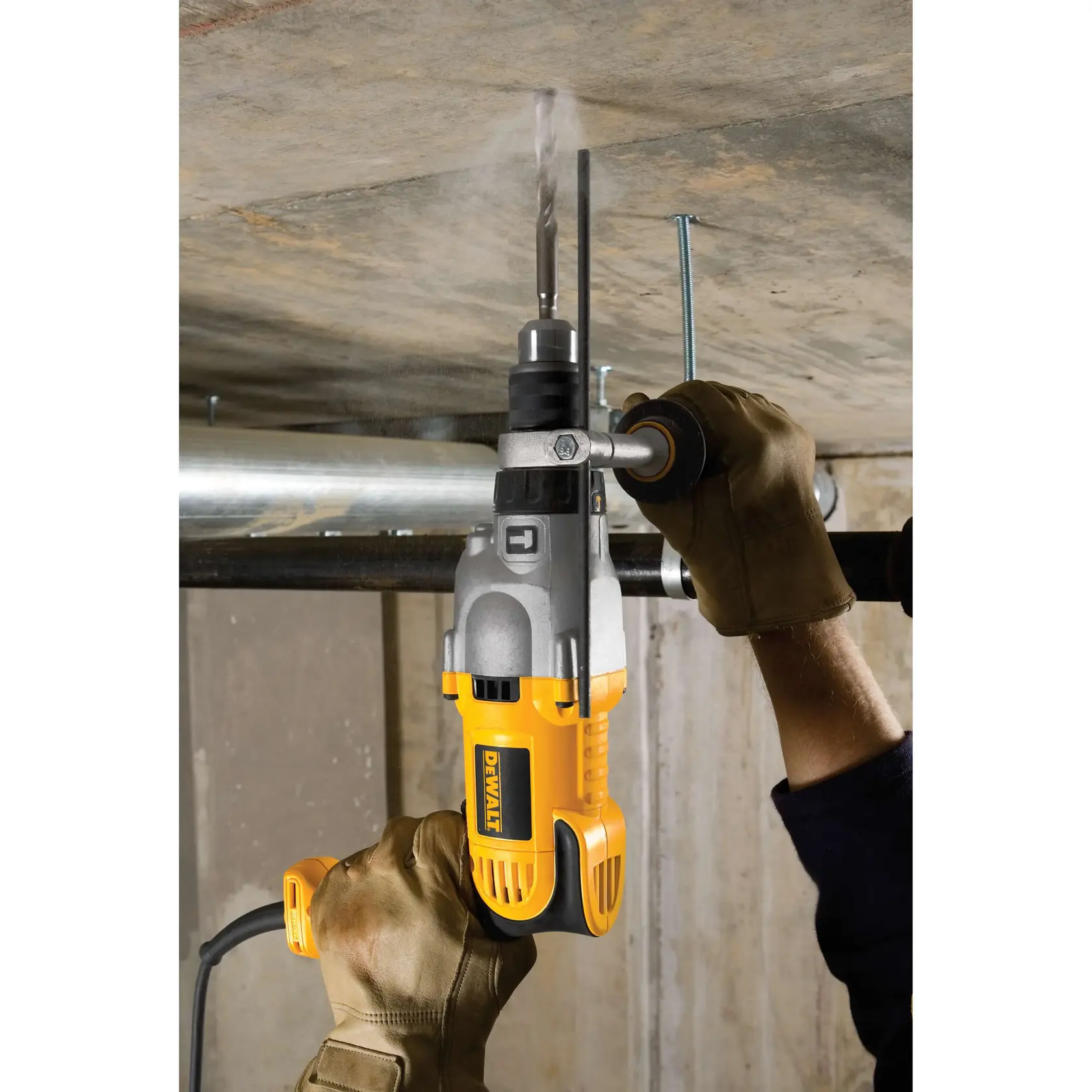 A person wearing brown gloves is using a yellow and black DEWALT electric drill to drill into a concrete ceiling.
