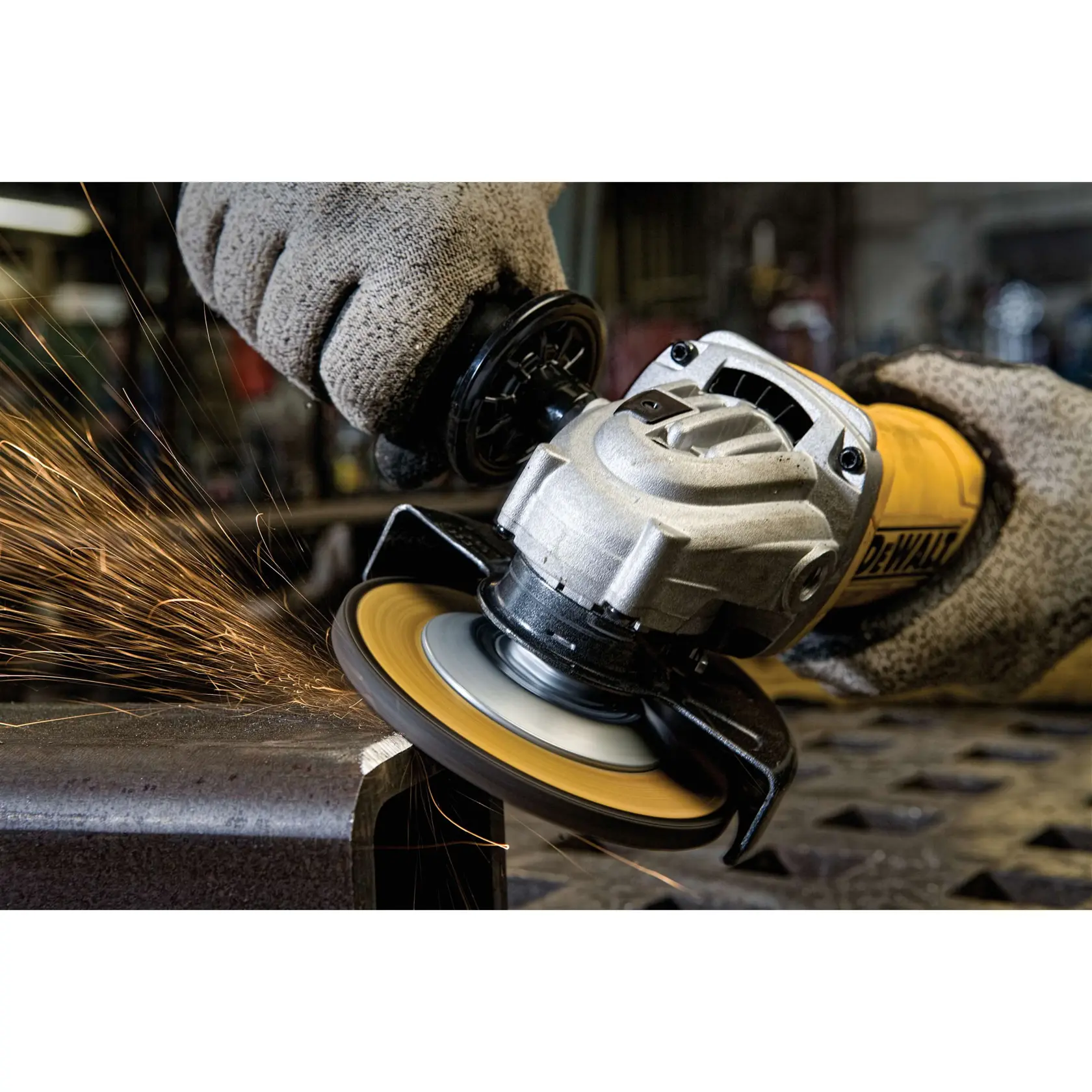 Close-up of a DEWALT angle grinder in use, producing sparks as it grinds a piece of metal. The operator is wearing protective gloves.
