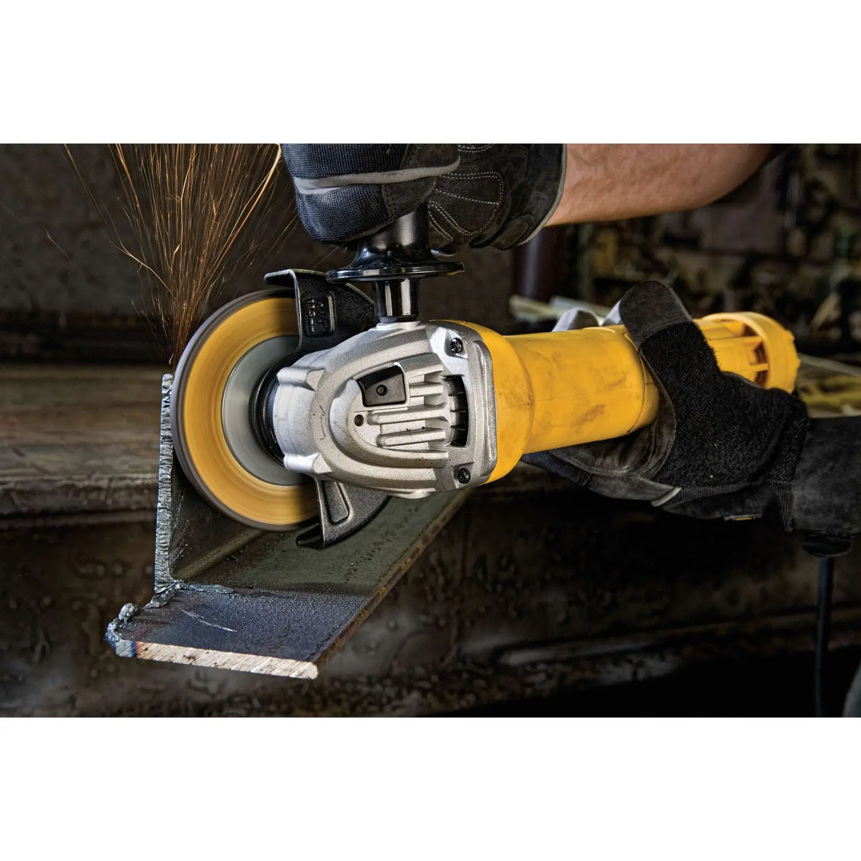 A person wearing protective gloves is using a DEWALT angle grinder to cut a metal piece, with sparks flying from the cutting area.