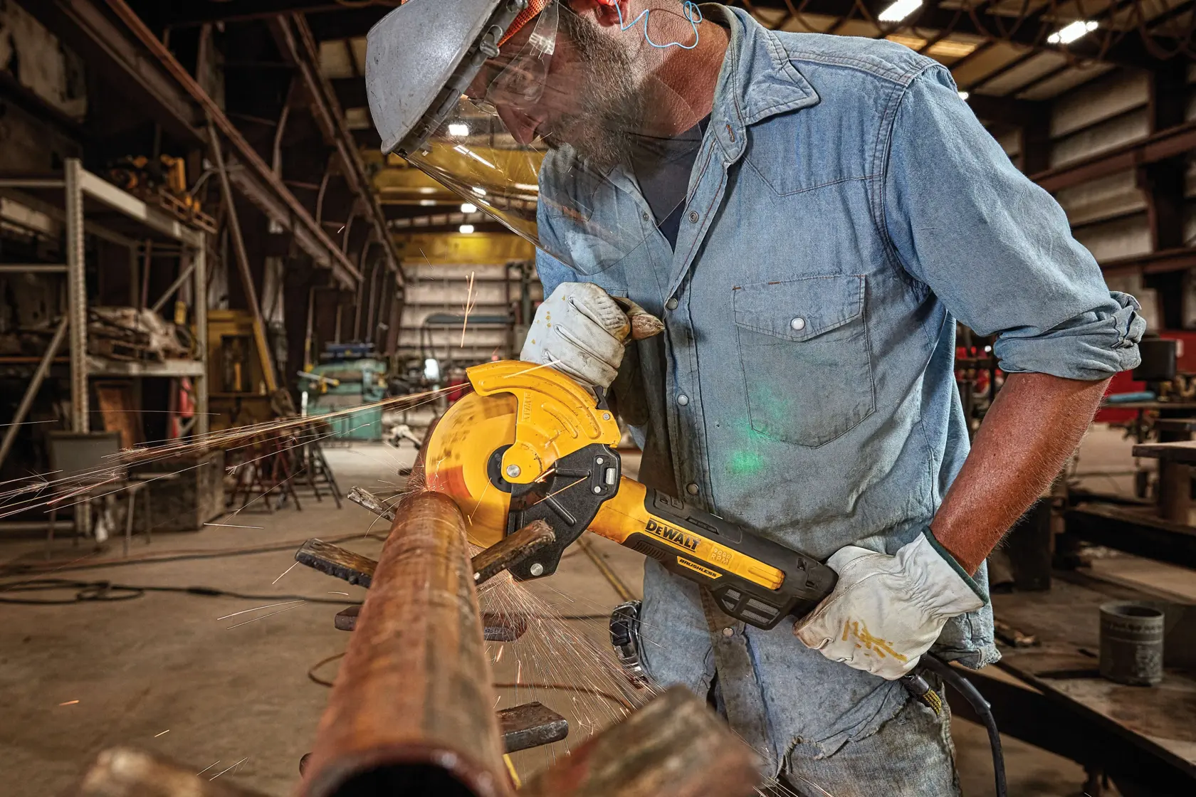 Person wearing safety gear uses a DEWALT power tool to cut a metal pipe in an industrial workshop, with sparks flying from the pipe.