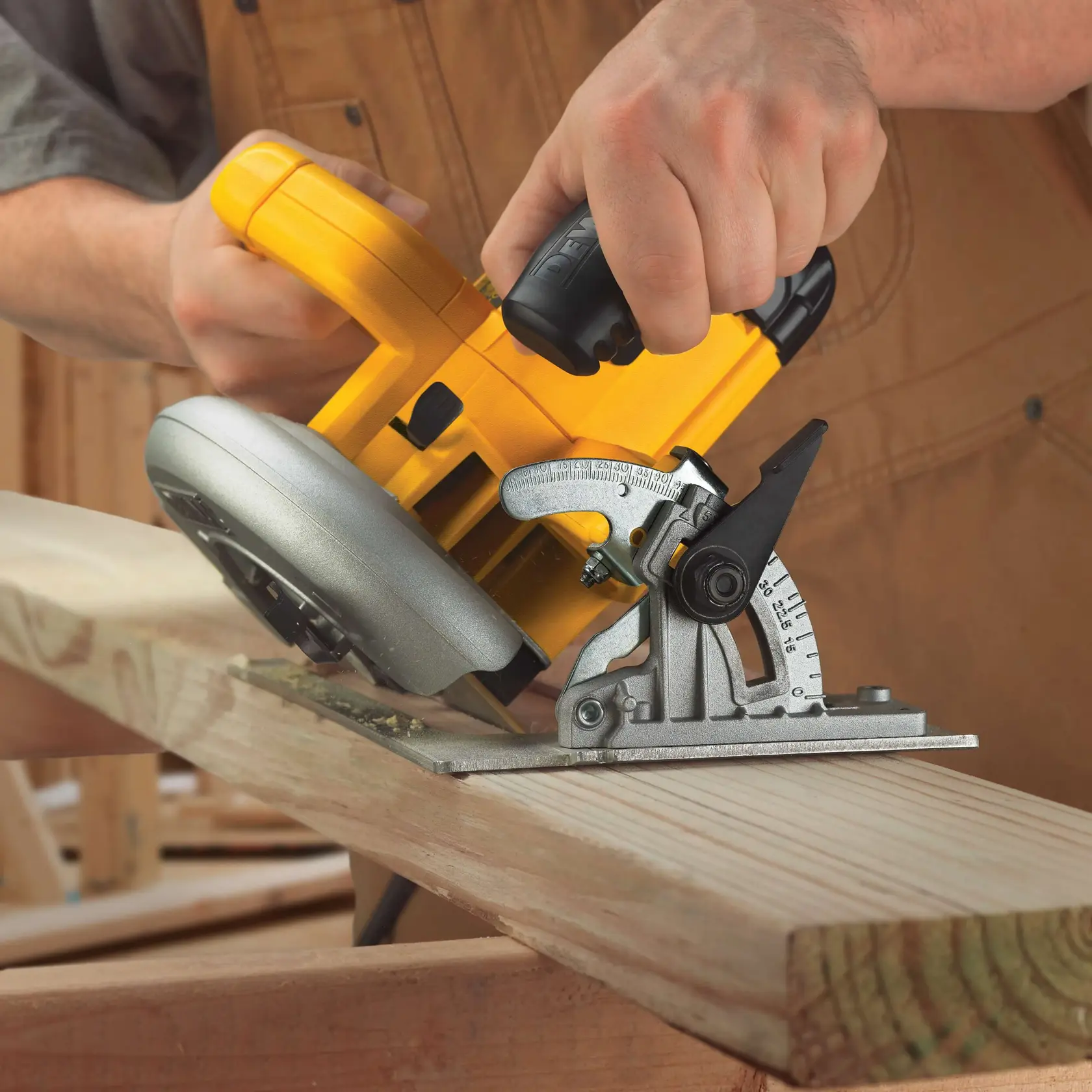 A person uses a yellow DEWALT DWE575 circular saw to cut a piece of wood at an angle. The saw's base plate and angle adjustment mechanism are visible, and the person is wearing a brown work apron.