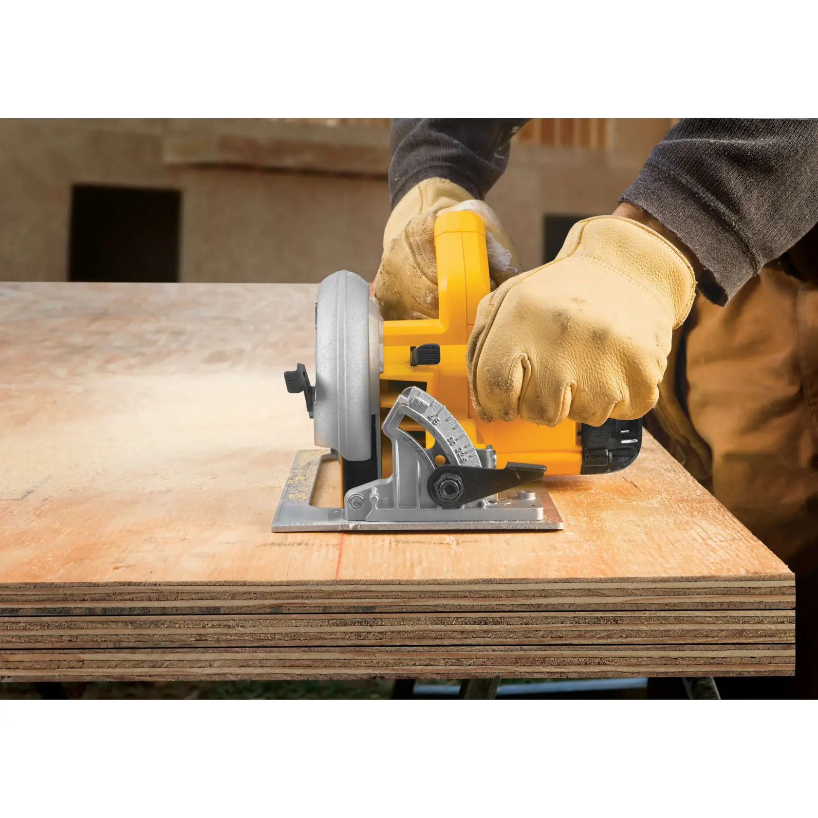 A person wearing work gloves is using a yellow DEWALT DWE575 circular saw to cut plywood sheets.