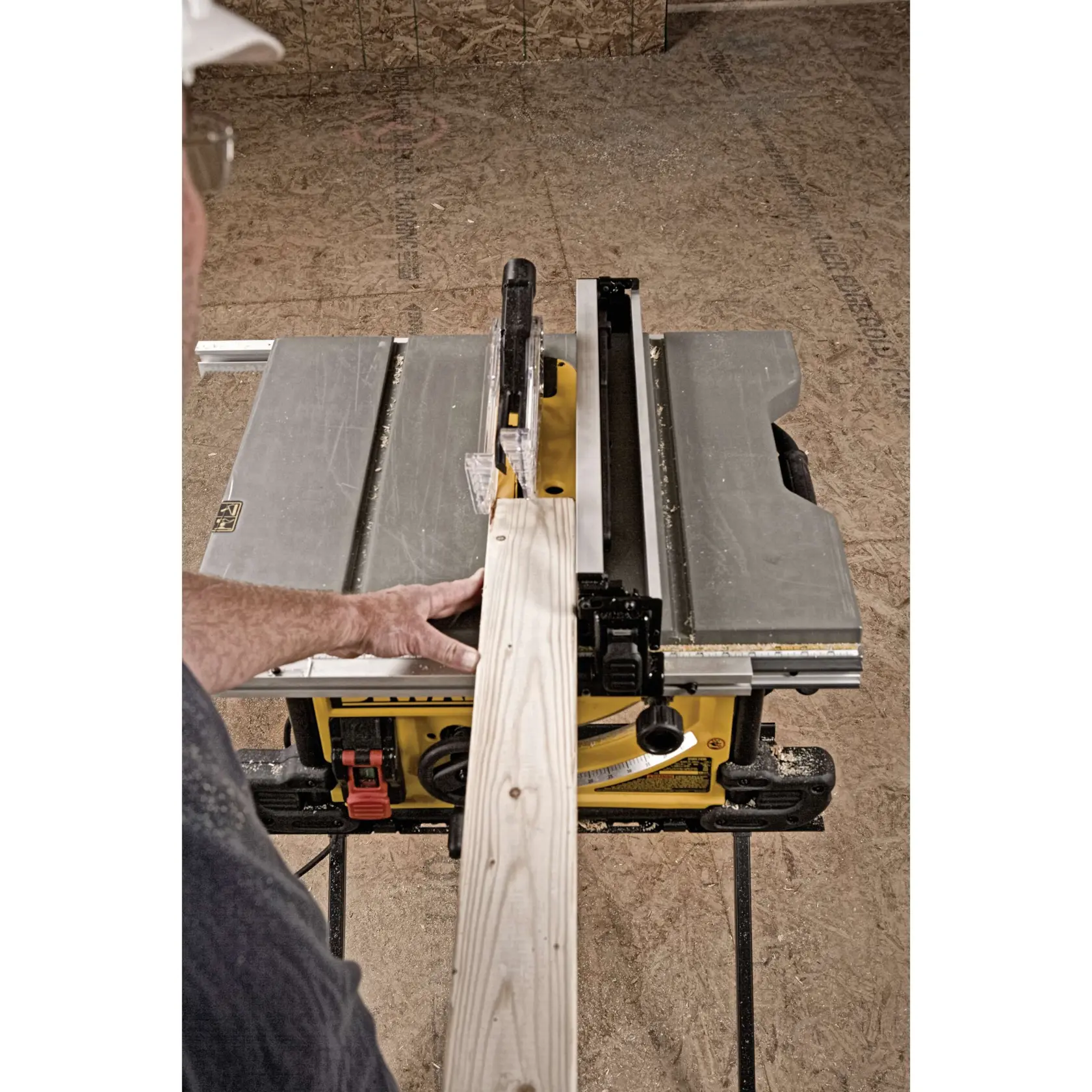 A DEWALT table saw being used to cut a wooden plank, with a person guiding the wood through the blade in a workshop.
