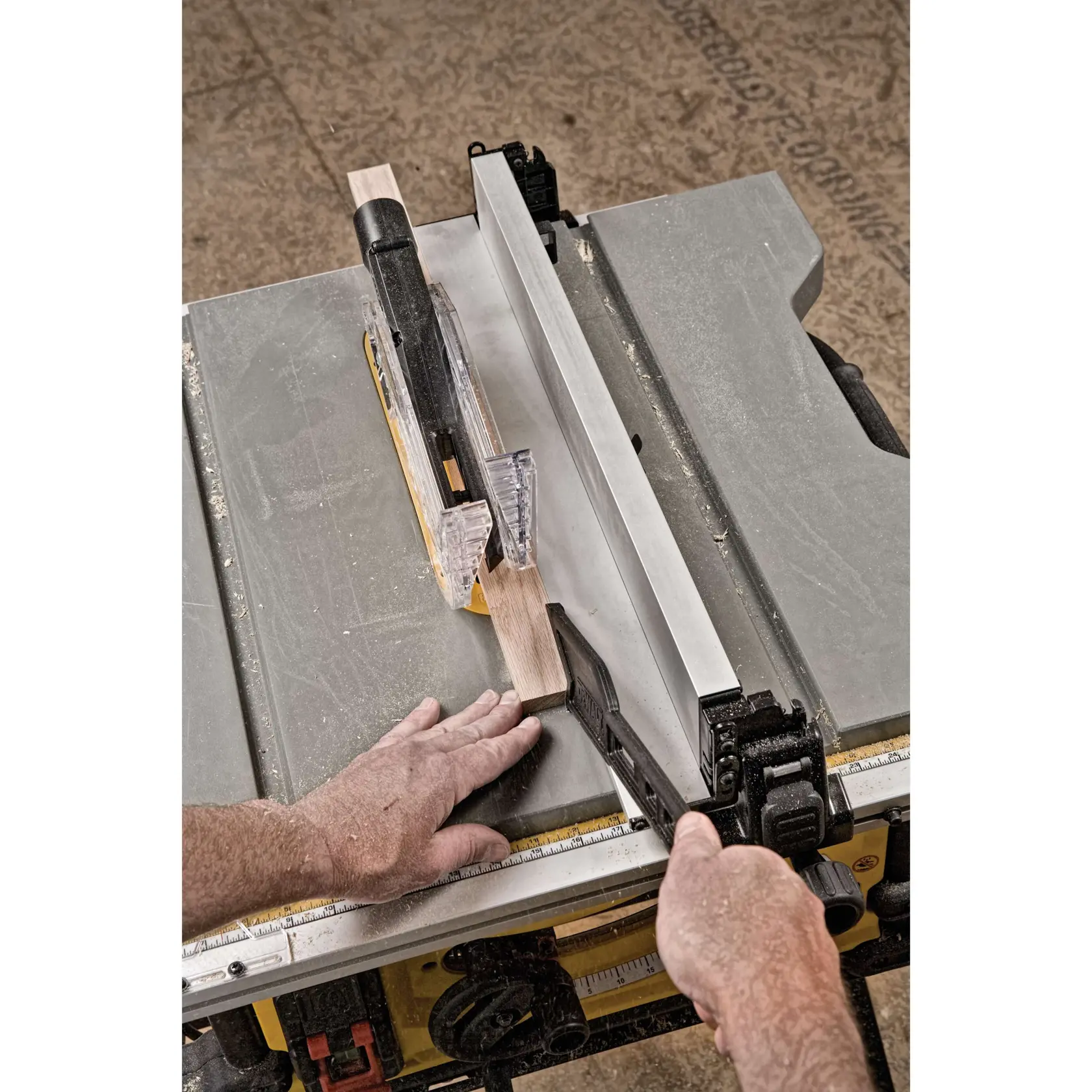 A person is using a DEWALT table saw (model DWE7491X) to cut a piece of wood, with a push stick and safety guard in place. The image shows the saw in action on a workshop floor.
