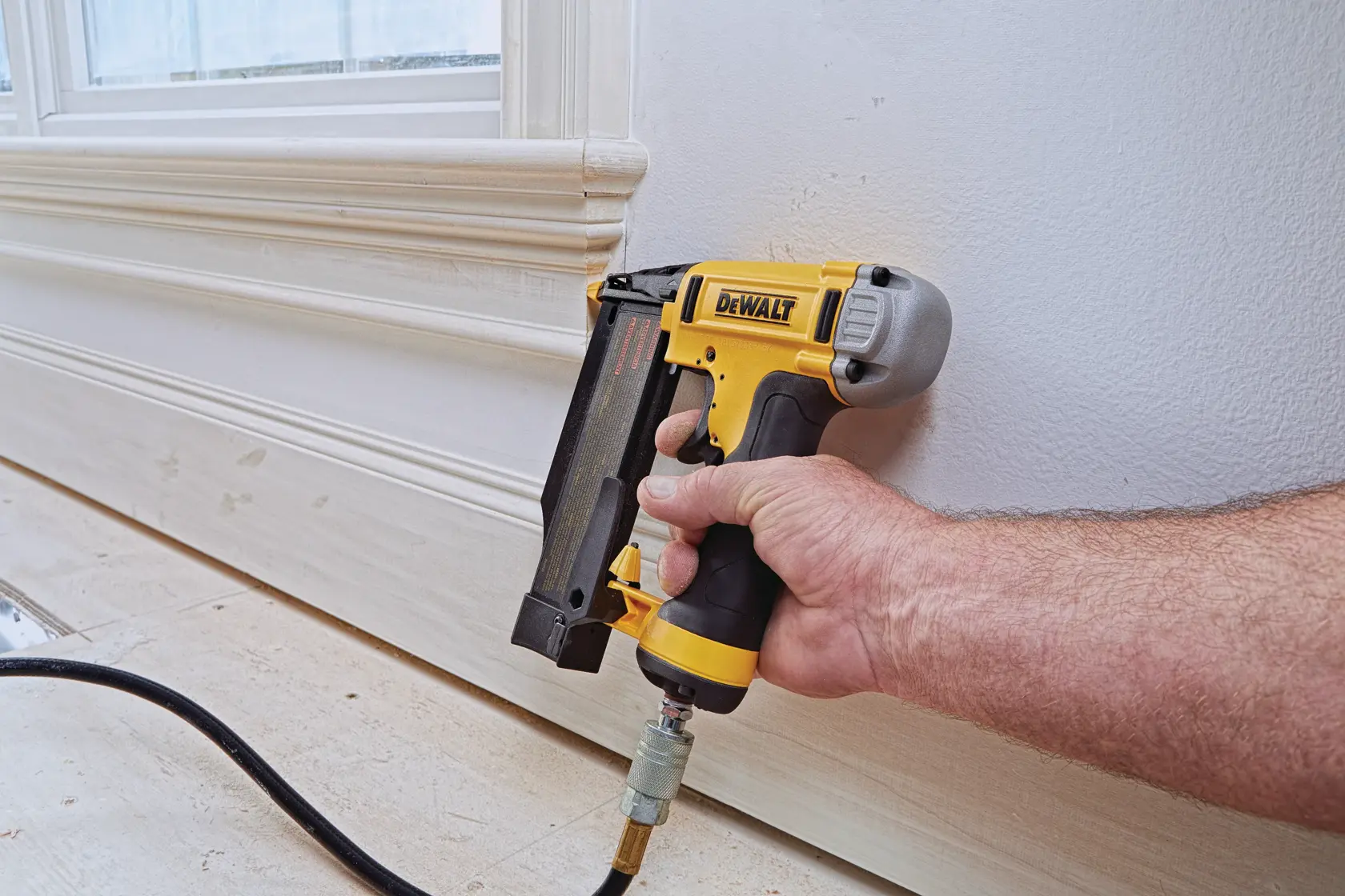 Close-up of a DEWALT DWFP2350K nailer, showing the tool-free jam release mechanism for easy nail removal. Highlighted text reads 'TOOL-FREE JAM RELEASE FOR EASY NAIL REMOVAL.'