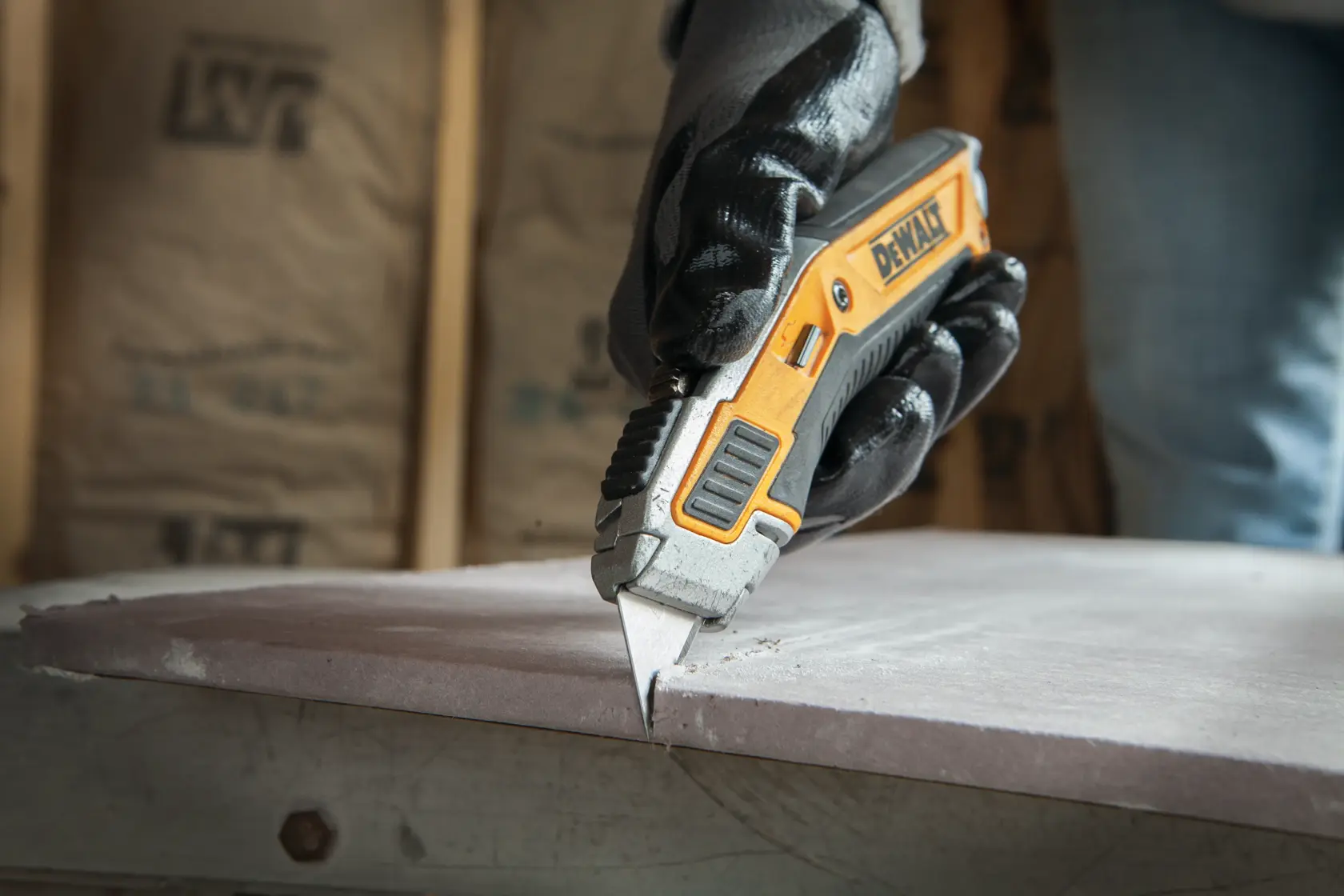Illustration showing blade storage instructions for a DEWALT utility knife. A hand is pushing a tab upward to release the top storage door, as indicated by a yellow arrow. Text below reads: '1. Push tab upward to release top storage door.'