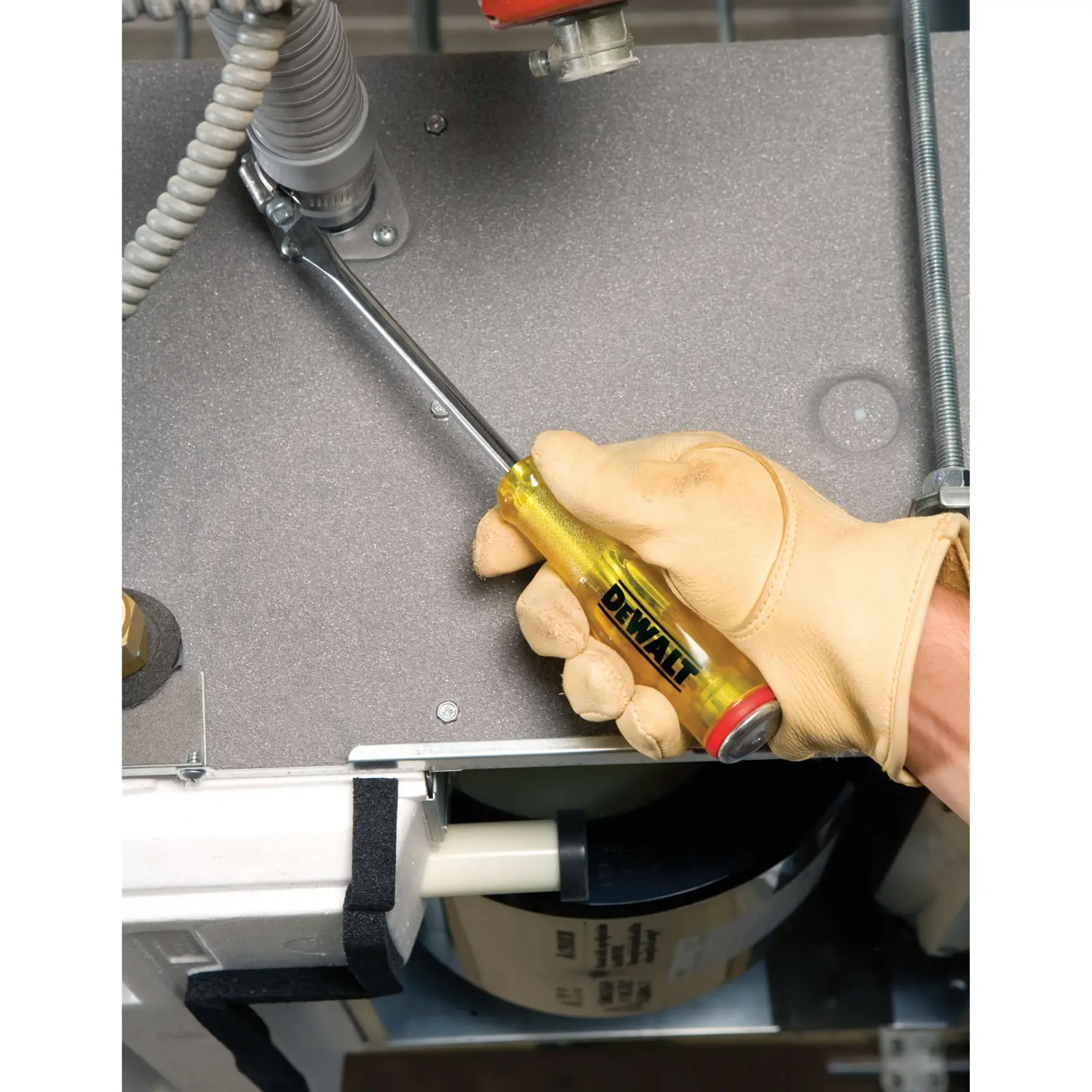 A gloved hand using a DEWALT screwdriver to tighten a metal connector on an electrical panel.