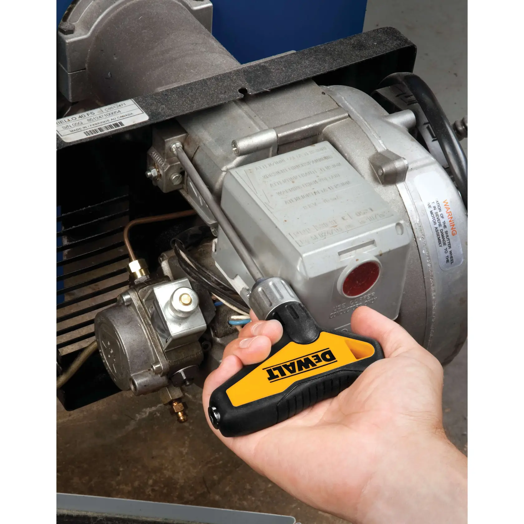 A hand holding a DEWALT T-handle ratcheting screwdriver is working on a metallic machine component.