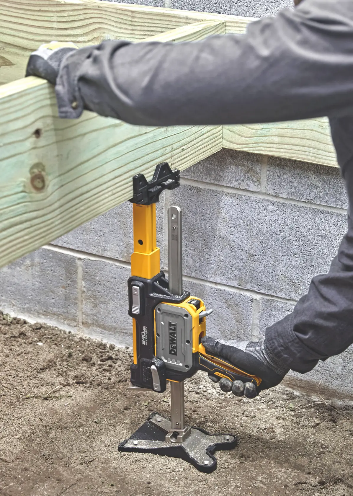DEWALT clamp secures wooden beam to concrete wall. Worker adjusts clamp using gloved hand at construction site.