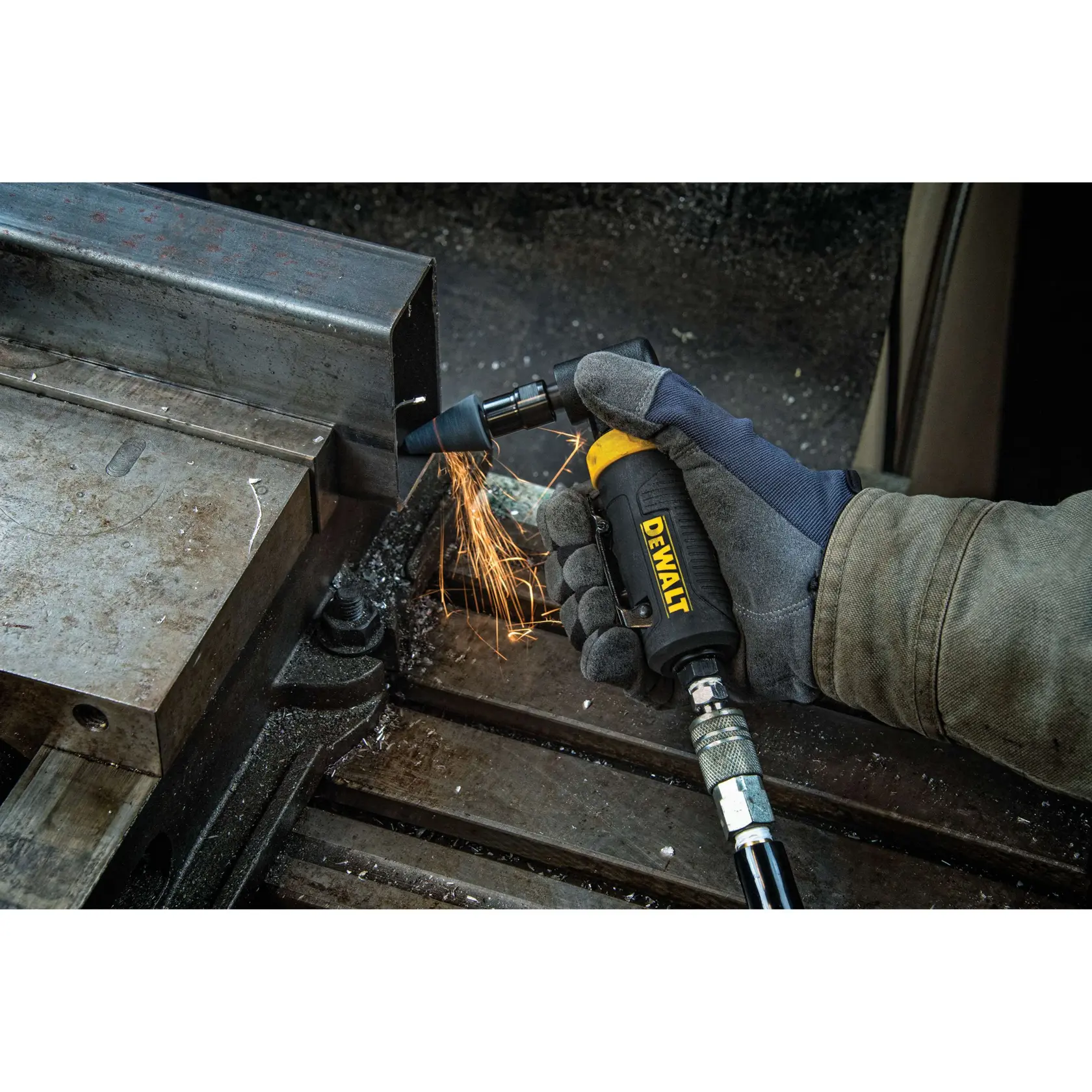 A person wearing protective gloves uses a DEWALT pneumatic angle die grinder to grind metal, producing sparks.