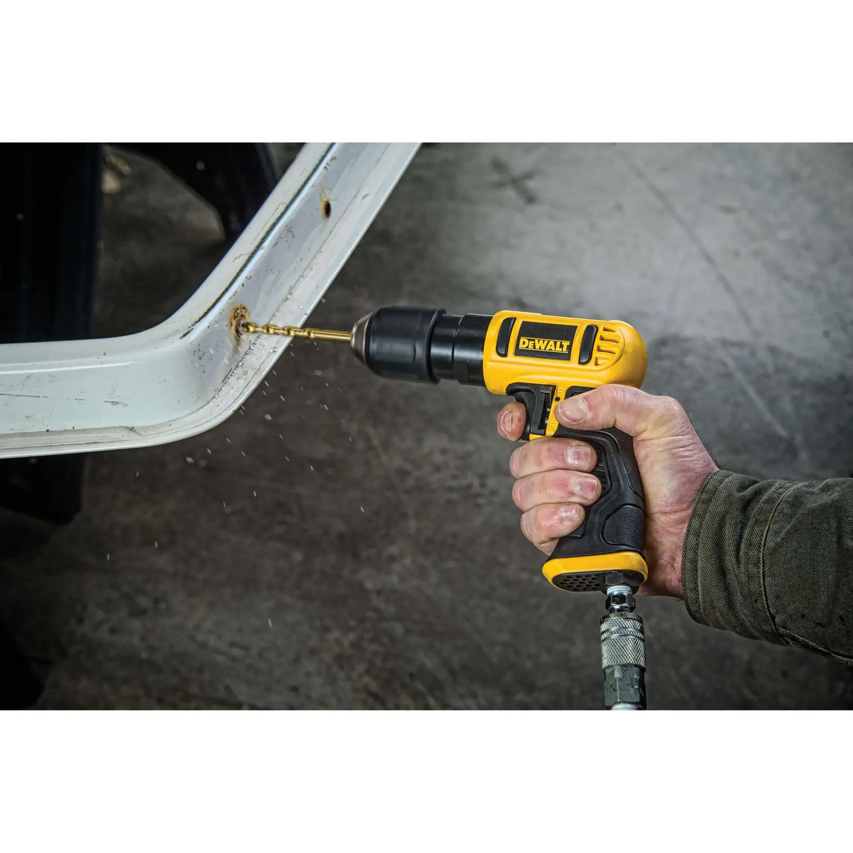 A person using a DEWALT pneumatic drill to drill into a metal surface. The drill is yellow and black, and connected to an air hose.