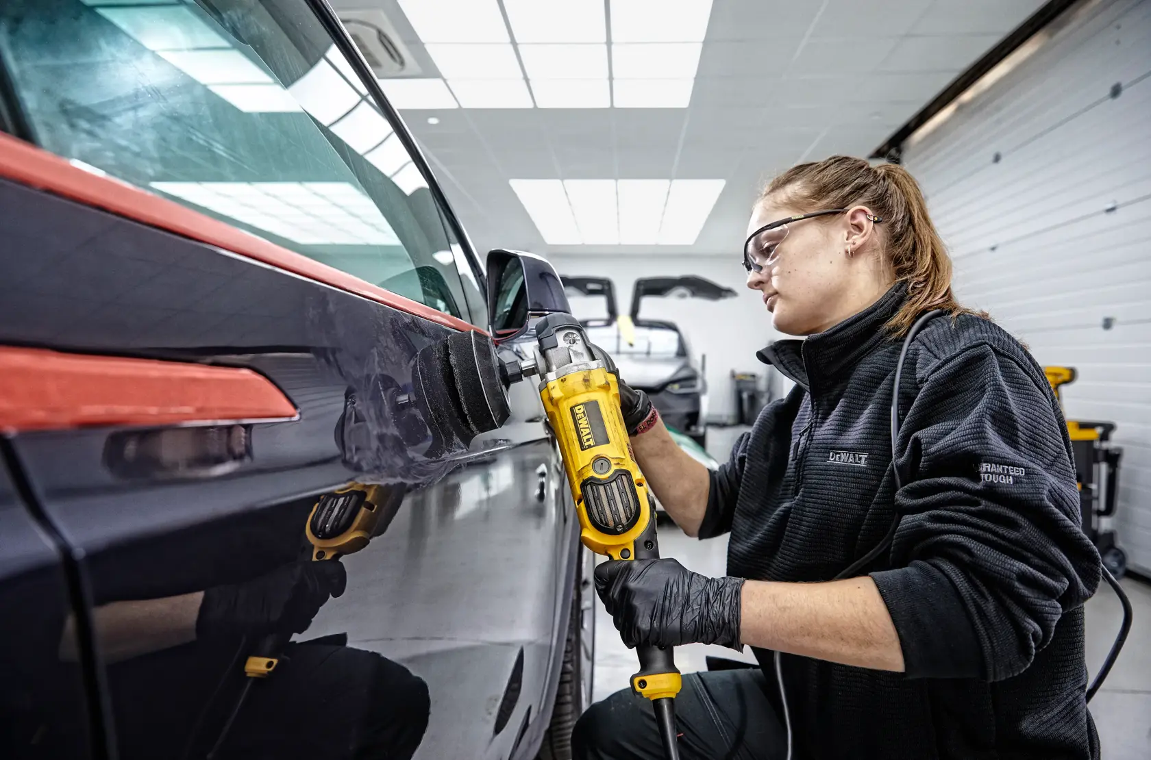 A DEWALT DWP849X variable speed polisher with a yellow and black design, featuring a side handle, positioned on a dark textured surface with the text 'Controlled Finishing System' in bold yellow letters.
