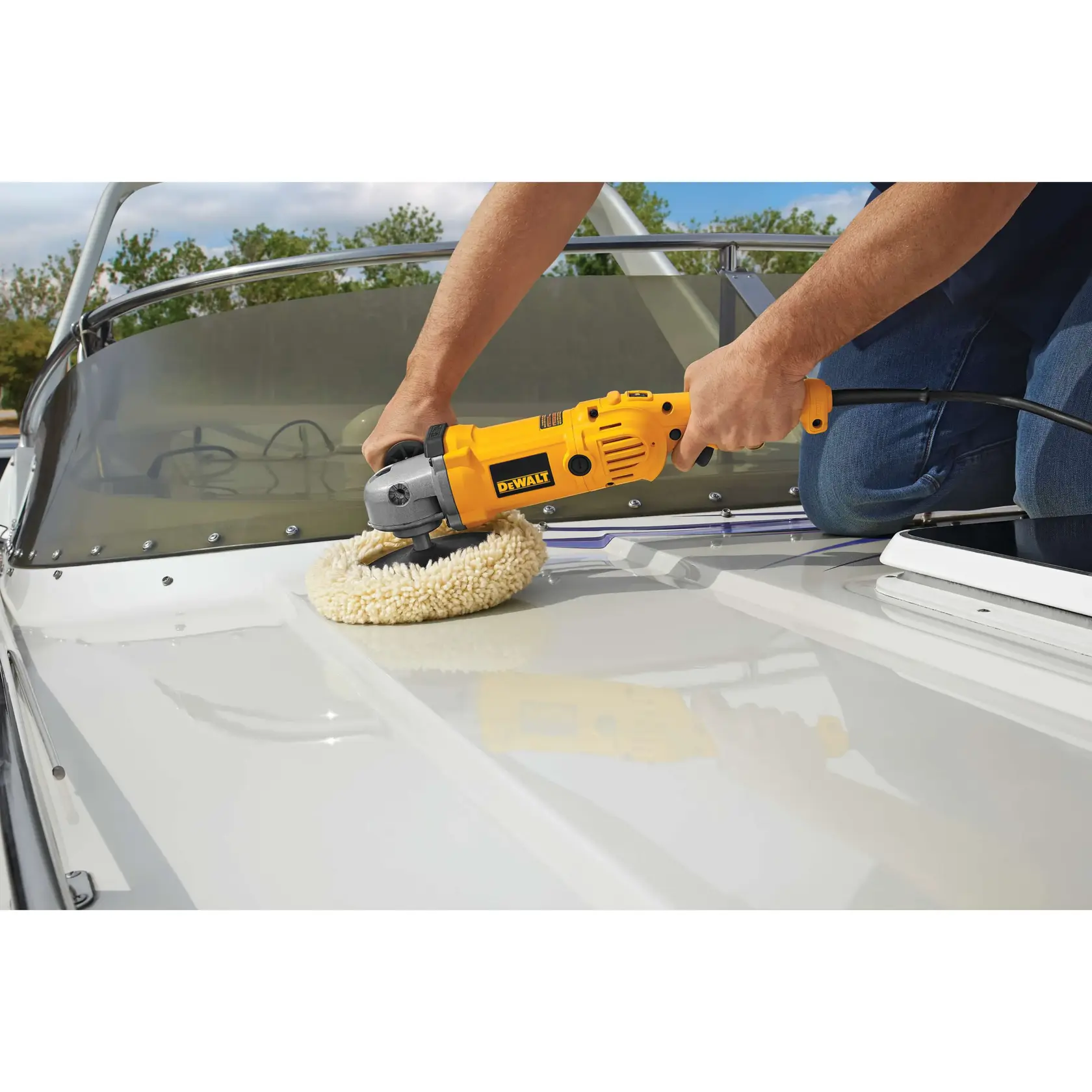 A person using a yellow DEWALT DWP849 polisher to polish the surface of a white boat.