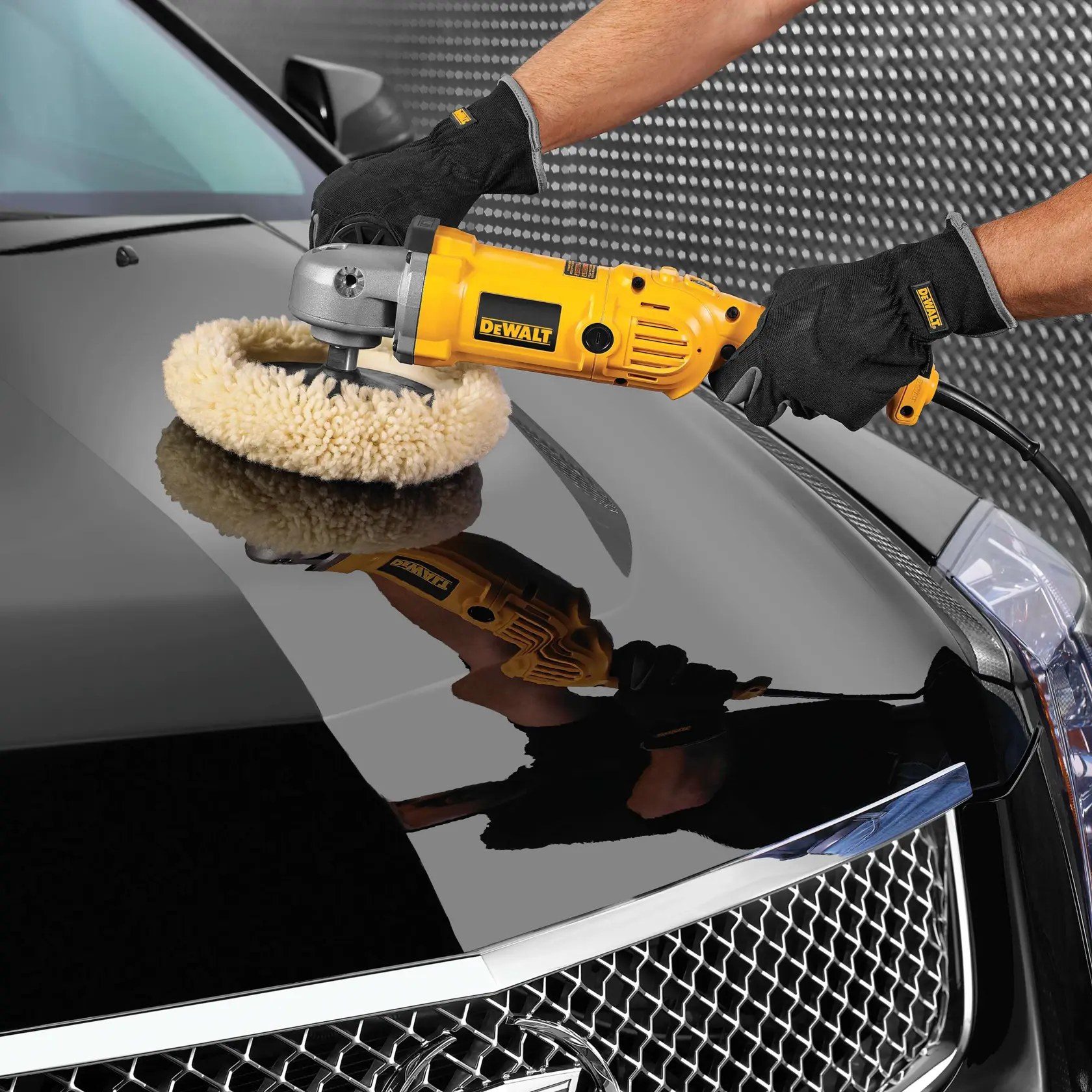 A person wearing black gloves uses a yellow DEWALT electric buffer to polish the shiny hood of a black car.
